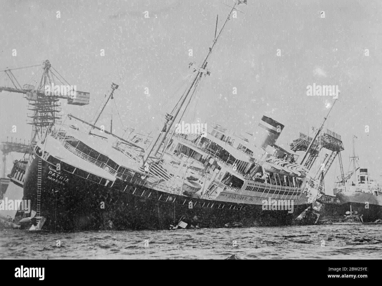 Le nouveau navire s'affiche soudainement dans le quai. Le nouveau navire électrique Hapag « Patria » se penchant sur ce qui semble être un angle dangereusement aigu après qu'elle ait soudainement développé une liste à quai à Hambourg. 11 juillet 1938 Banque D'Images