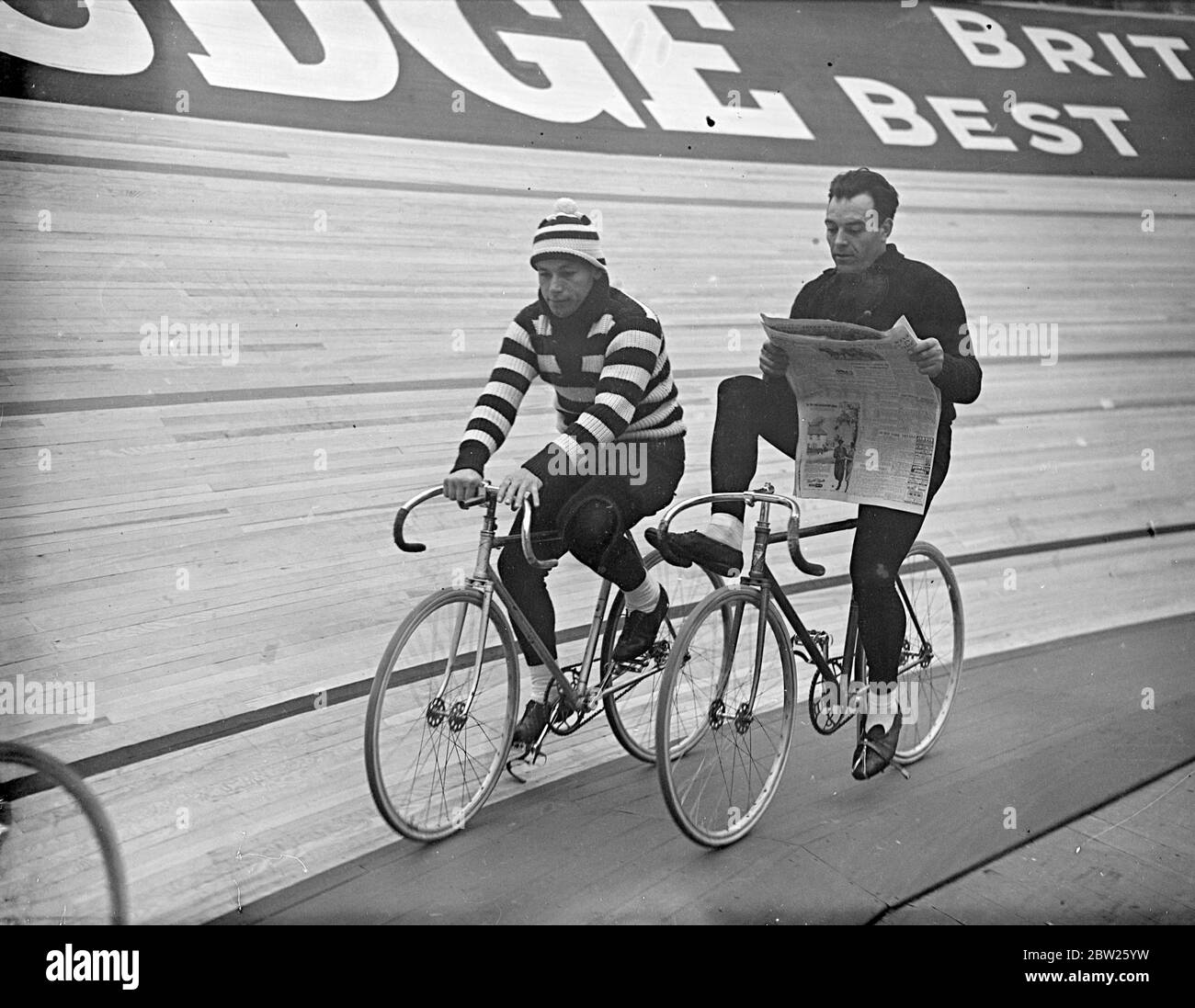 Lecture d'une roue en six jours de course à vélo à Wembley. La deuxième course de six jours est en cours à l'Empire, Pool, Wembley, après avoir commencé quelques minutes après minuit. Photos, Piet Van Kempen (Hollande) lisant un journal en parcourant la piste. Michel Pecqueux (France) en jersey rayé est à côté. 2 mai 1938 Banque D'Images