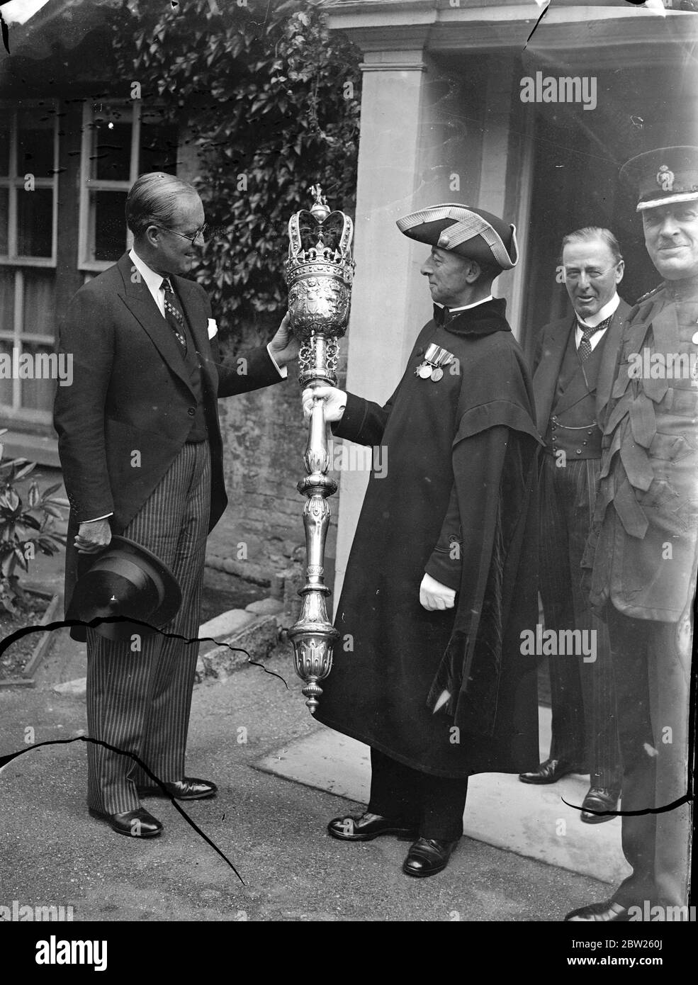 M. Joseph P Kennedy, ambassadeur américain, Dévoilée dans la cathédrale de Winchester, une vitrail qui a été donné à la cathédrale par les Américains en hommage à la vie et au caractère du roi George V. l'une des lumières contient une représentation de la figure à genoux du roi portant les robes de l'ordre de Le Garter'. La fenêtre est le travail de M. Hugh Easton. Expositions de photos, M. Joseph P Kennedyinspectant la Winchester City Mace, la deuxième plus grande au monde, lors de sa visite. 12 juillet 1938 Banque D'Images