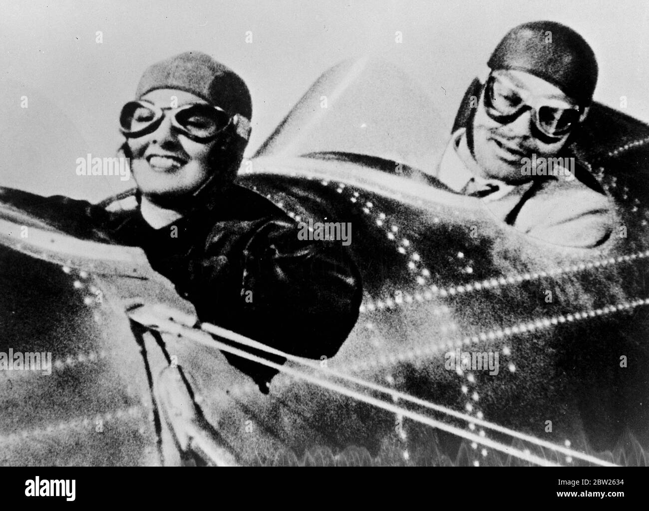Vaisseau d'audience aérien, à l'étage du studio. Cette série de photos montre le tourbillon d'un tribunal dans le cockpit d'un avion de Myrna Loy et Clark Gable, le daredevil pilote, se présente à Myrna Loy , quand il a forcé des terres est avion dans un champ. L'avion est censé être un mile haut comme Gable donne une leçon de vol à Myrna Loy, mais les prises de vue ont été faites dans une machine spéciale sur le studio. Expositions de photos, Clark Gable, le pilote d'essai de daredevil regarde complaisamment tandis que son 'élève', Myrna Loy met l'avion dans une plongée de puissance. Banque D'Images