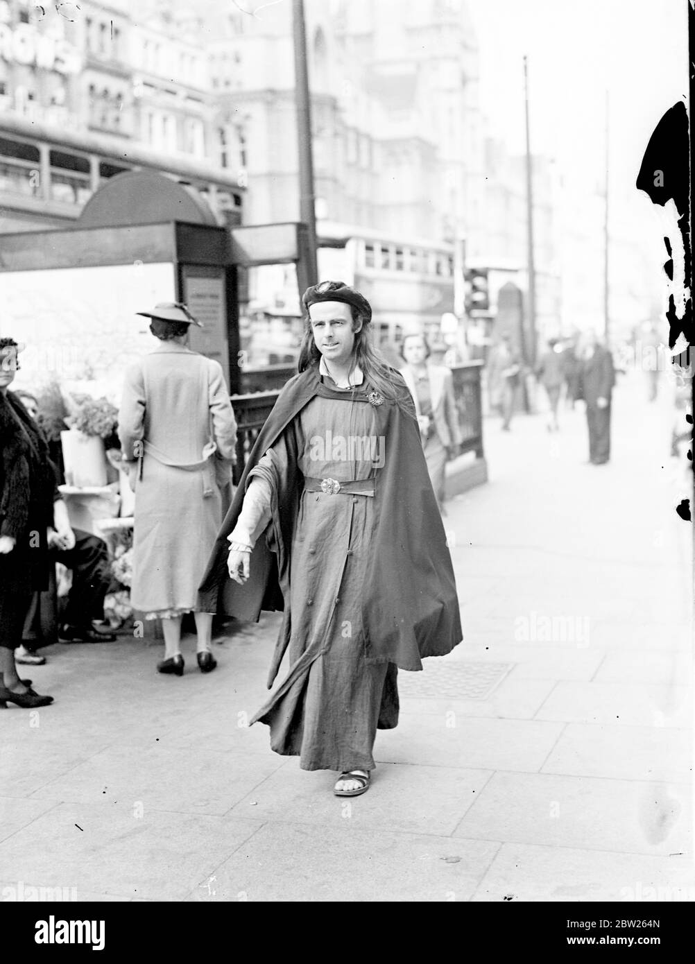Apporte le Moyen Age à Londres. Le comte Potocki de Montalk, poète et écrivain polonais, qui est l'une des figures les plus pittoresques de Londres, traverse Holborn dans le costume médiéval, qui est son vêtement de tous les jours. Le costume lui-même semble être un peu "chaud" pour la femme, mais les sandales semblent assez confortables. 5 août 1938 Banque D'Images