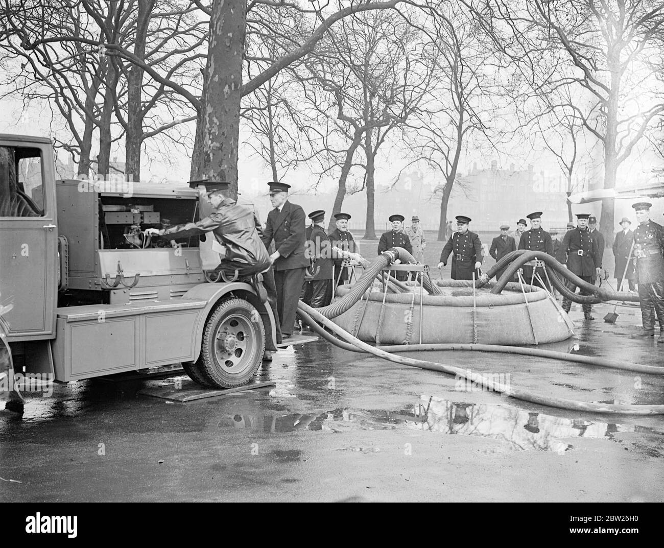 Le pompier de Londres ont un exercice RAID anti air avec une nouvelle pompe. Des pompiers effectuent actuellement des exercices réguliers avec les unités de pompage du gouvernement à Battersea Park, Victoria Park et Hyde Park dans le cadre du travail de précautions contre les raid aériens de la brigade des pompiers de Londres, pour laquelle un département spécial a été créé dans la brigade. Le pompage de l'eau sur de longues distances sera l'un des facteurs les plus importants en cas de raids, lorsque le réseau pourrait être détruit. Les piscines en toile sont utilisées pour le relaring de l'eau des canaux de rivières. Des spectacles de photos, un pompier, tester la nouvelle piscine de toile, ou « suis » comme c'est calle Banque D'Images