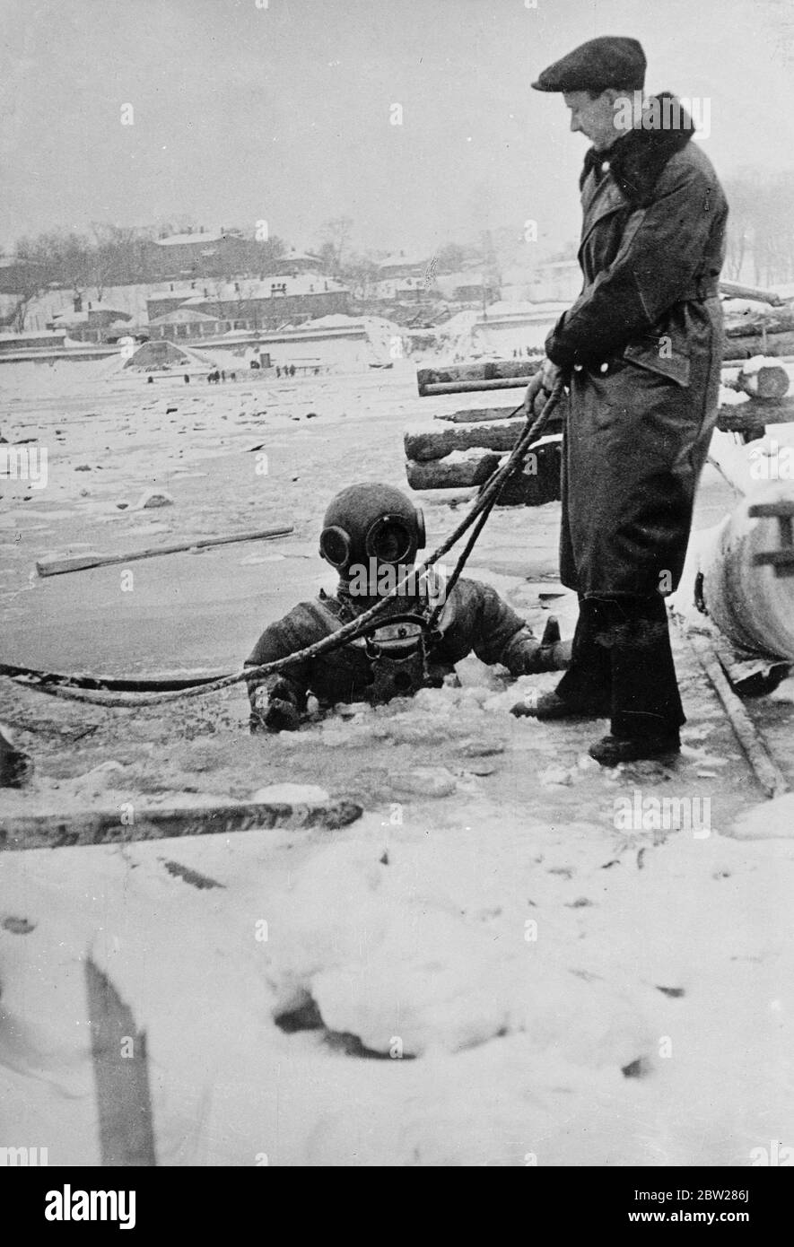 Plongée sous la glace de la rivière de Moscou. Bien que la rivière de Moscou soit épaisse et recouverte de glace, les travaux de pose des tuyaux d'égout et de gaz sous le lit de la rivière sont effectués par des plongeurs. Le travail, qui est réalisé par Epron (le Soviet Ships Salvaging Trust) est très dangereux pour le plongeur. Si par accident il doit être coupé à la dérive de la station de rivage il pourrait assez facilement dériver sur des kilomètres sous la glace sans espoir de sauvetage. Mais les spectacles, un plongeur descendant par un trou dans la glace de la rivière de Moscou. Notez la glace sur la ligne de vie. 12 janvier 1938 Banque D'Images