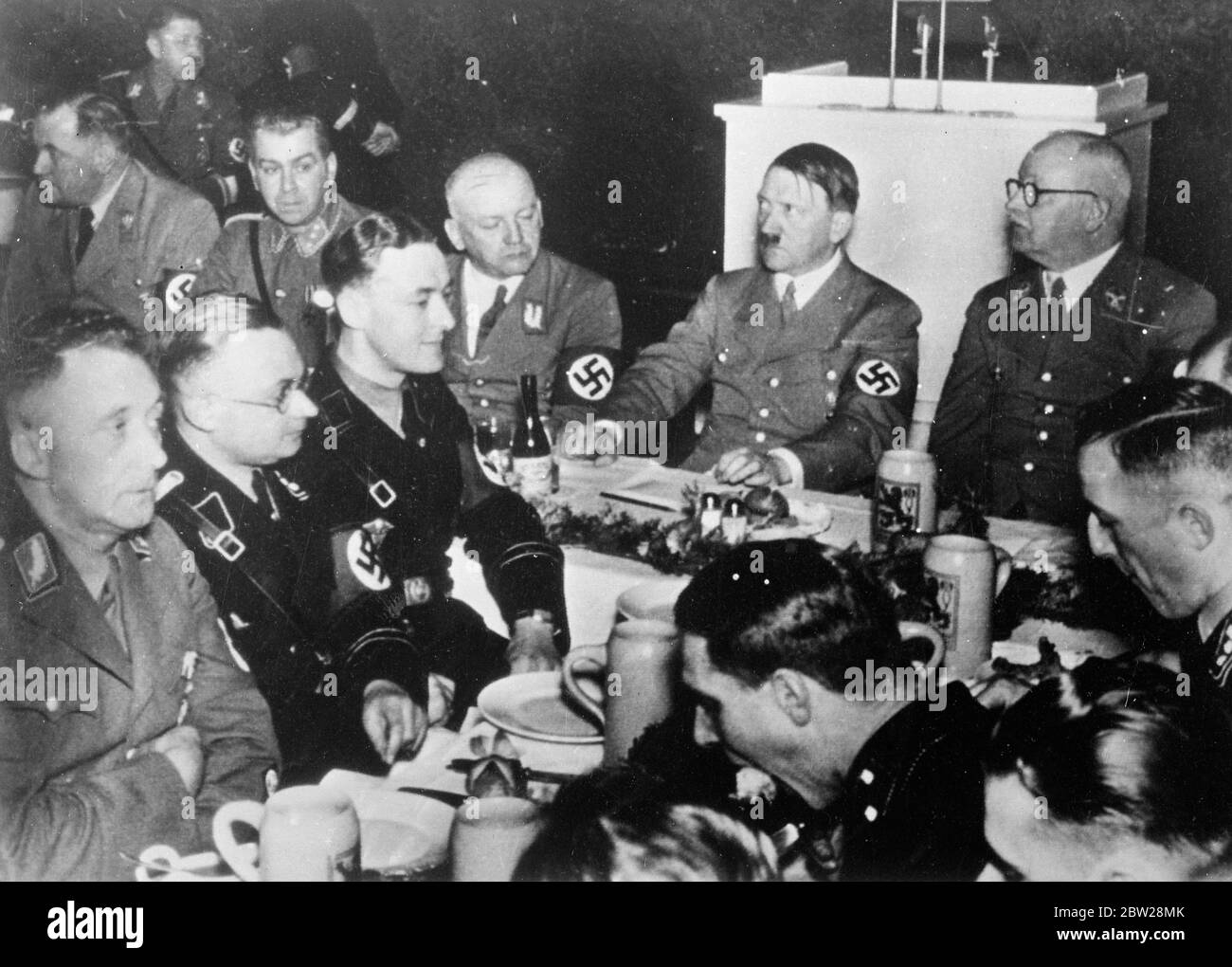 Hitler à la fête de Noël avec "vieux camarade". Hitler a présidé la fête de Noël dans la brasserie Lowenbrau de Munich, en présence des anciens combattants nazis du putsch de 1923. Des séances de photos, le chancelier Hitler préside la fête. A gauche d'Hitler, se trouve le chef de district Adolf Wagner, et l'extrême gauche est sur le chef de groupe Bruckner. Le droit d'Hitler est le maître du Trésor de Reich Schwarz. 27 décembre 1937 Banque D'Images