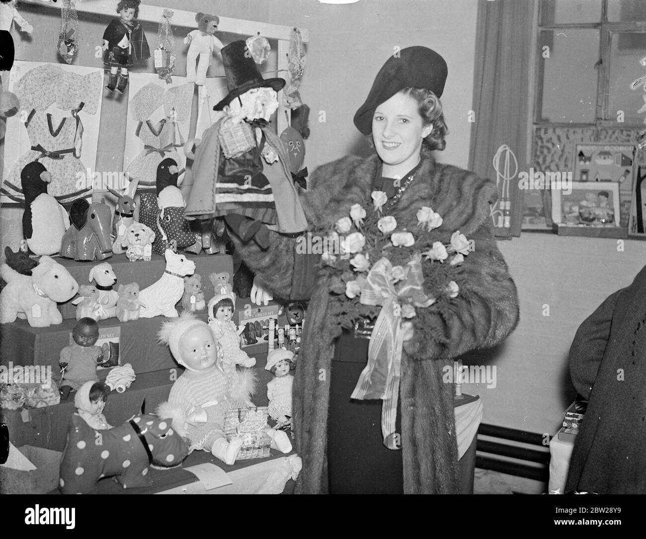 Actrice ouvre la foire de Noël à la clinique de Tavistock. Mlle leonora Corbett, la scène et actrice du film, qui est actuellement dans 'Sarah simple', a ouvert la foire de Noël en aide à la clinique de Tavistock, Malet Street, Bloomsbury. Spectacles de photos, Leonora Corbett avec une poupée vêtue en costume gallois dans l'un des stands de la clinique de Tavistock. 27 novembre 1937 Banque D'Images
