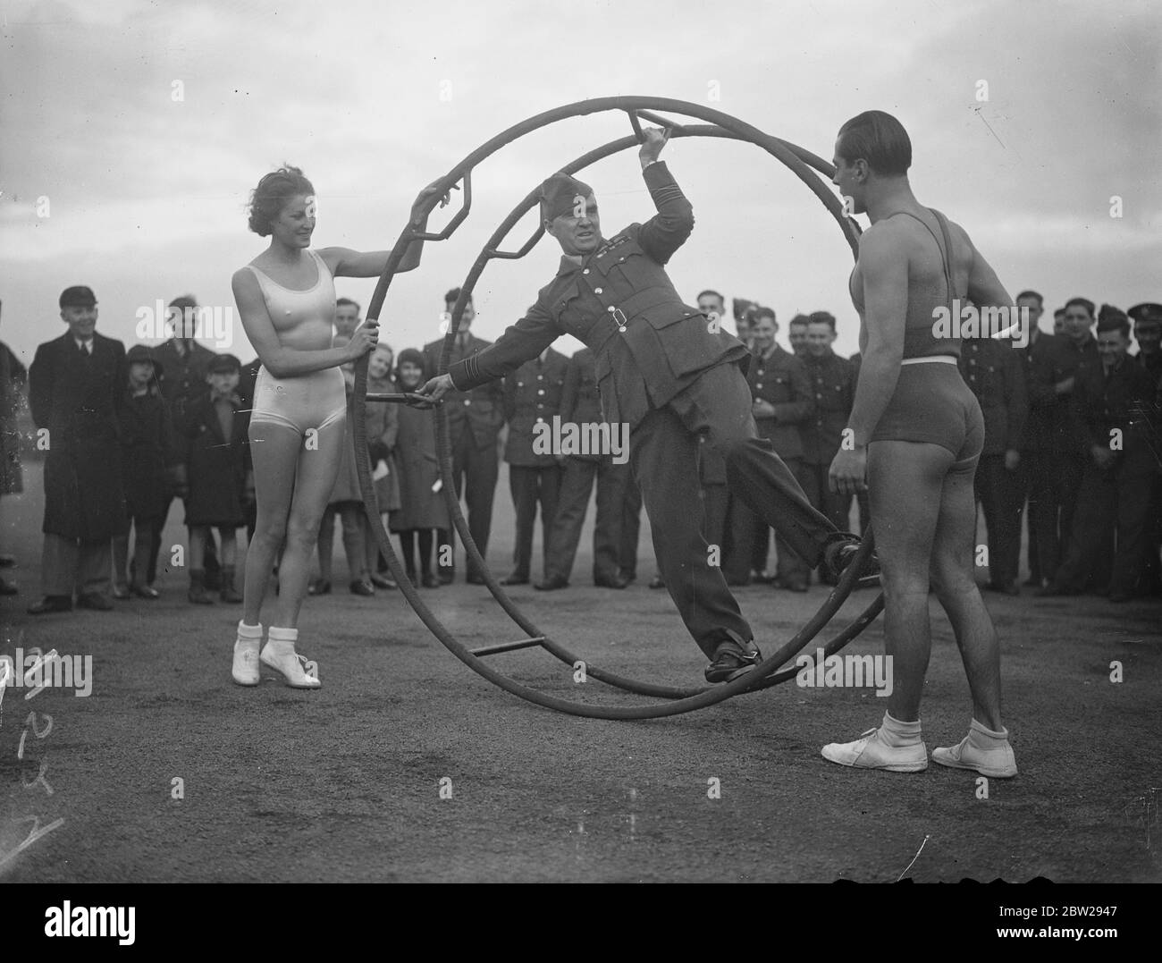 Les filles allemandes montrent aux apprentis de la RAF une nouvelle façon de garder la forme. Une équipe de filles allemandes, les 'Rhoenrads', qui ont été présentés à Londres, a envahi la station de la RAF à Cranwell, à l'invitation du commandant de l'escadre JR Cassidy de faire une démonstration des nouveaux moyens d'améliorer la forme physique aux apprentis du centre. Les filles exécutent des roues ongyro, qui sont utilisées pour enseigner l'équilibre dans toutes sortes de positions. Photos, commandant de l'escadre J R Cassidy montrant comment utiliser les roues de gyroscope par les filles à RAF Cranwell. 27 novembre 1937 Banque D'Images