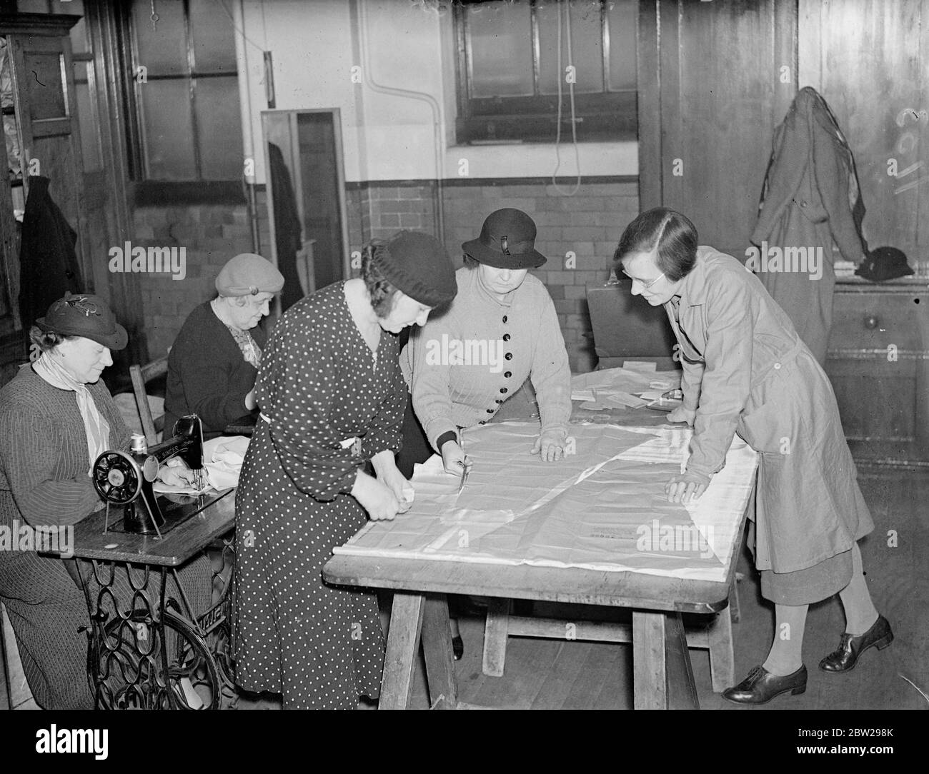 École de Londres où les femmes peuvent apprendre à être de bonnes épouses. Une école spéciale. Enseigner aux femmes à être de bonnes femmes est mené à la rue Sayer, Women's Institute, Wolworth. Les cours, beaucoup d'entre eux sont des cours de soirée incluent tout, de la cuisine au travail du bois. Les élèves de 15 à 90 ans vont à l'école, même s'il ne s'agit que d'un cours 'plus frais'. Il y a beaucoup de grands-mères qui prennent des cours de cuisine. Deux jeunes femmes assistant à des cours de travail du bois ont fait pratiquement tout pour une suite de chambre. Expositions de photos, étudiants au travail dans la classe de travail dans les aiguilles. 22 novembre 1937 Banque D'Images
