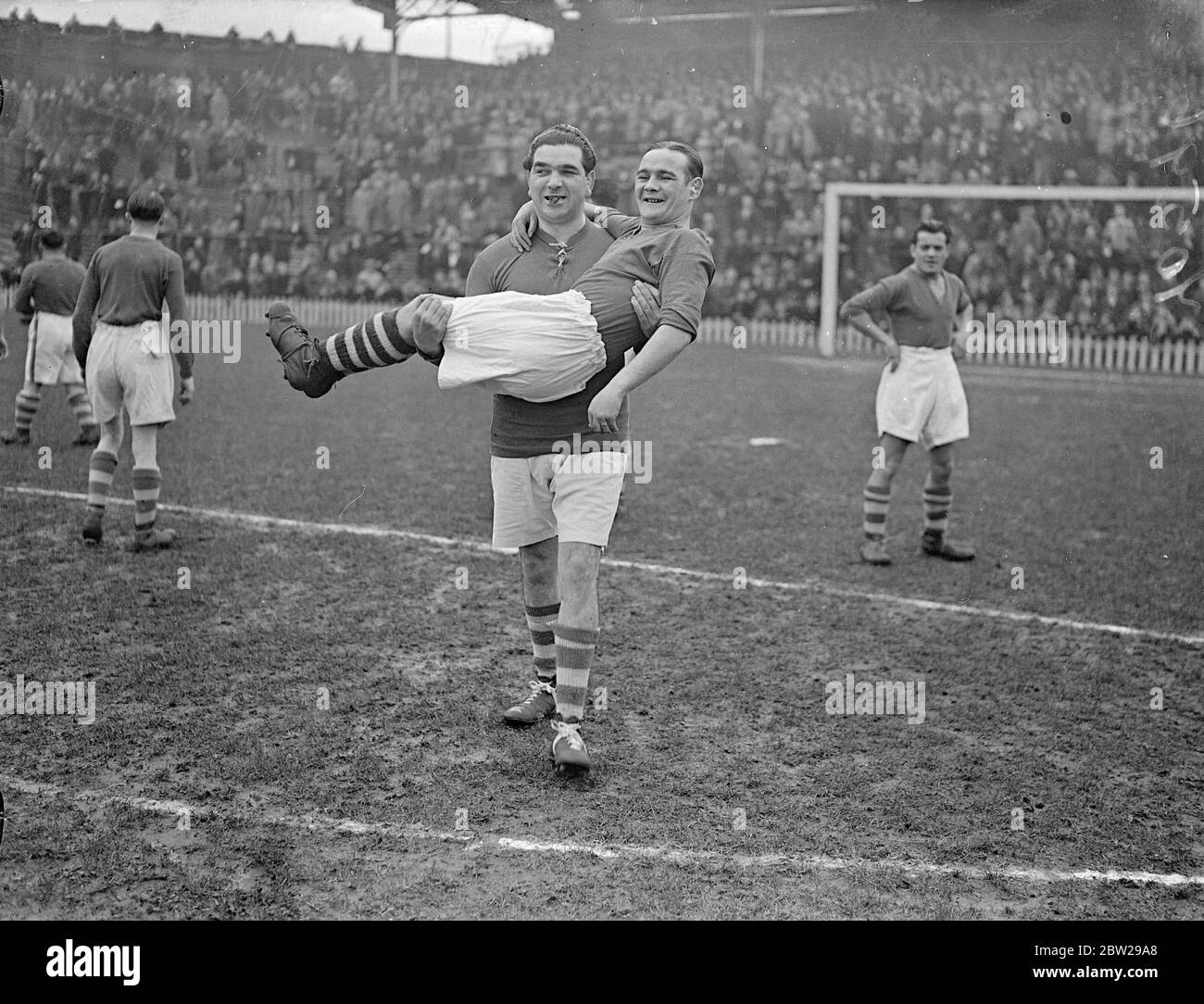 « porter » au match de football des jockeys contre des boxeurs. Le match de football annuel de charité entre des jokeys et des boxeurs connus a été joué au terrain du club de football de Millwall, la Nouvelle Croix. Expositions de photos, Jack Bloomfield, le capitaine des boxeurs, portant Benny Lynch, le champion du monde de poids-mouche, sur le terrain. 25 octobre 1937 Banque D'Images