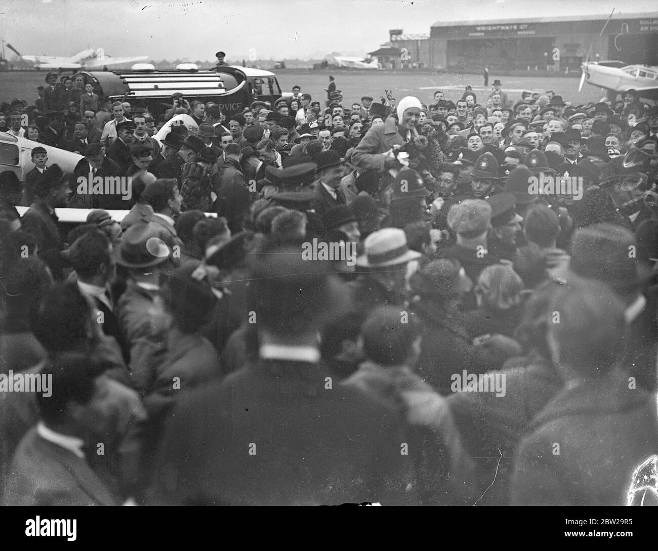 Jean Batten fait 14 1/2 heures de route pour l'Australie et l'Angleterre. Après avoir lutté contre l'épuisement et les galettes sur son dernier tour éprouvant, Jean Batten, la jeune fille aérienne néo-zélandaise, a été accueillie par des foules enthousiastes lorsqu'elle a atterri à Croydon après avoir battu le record de Jim Broadbent de l'Australie en Angleterre de 14 1/2 heures. Elle avait atterri à Lympne, effectuant son premier vol solo en cinq jours et 18 heures, et est arrivée à Croydon. Des expositions de photos, Jean Batten étant porté par la foule Mensa à Croydon. 24 octobre 1937 Banque D'Images