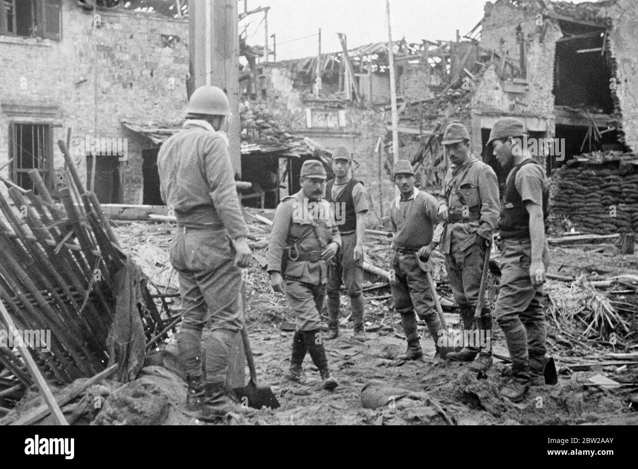 La lecture avec prudence dans les ruines-recherche japonaise de Chinois sur les mines terrestres. Une fête japonaise « qui se déroule » avec des pelles lorsqu'elles ont mené une recherche minutieuse de mines terrestres et de grenades, laissées derrière elles par les troupes chinoises en retraite au milieu des ruines tumultes de Shanghai. 6 décembre 1937 Banque D'Images
