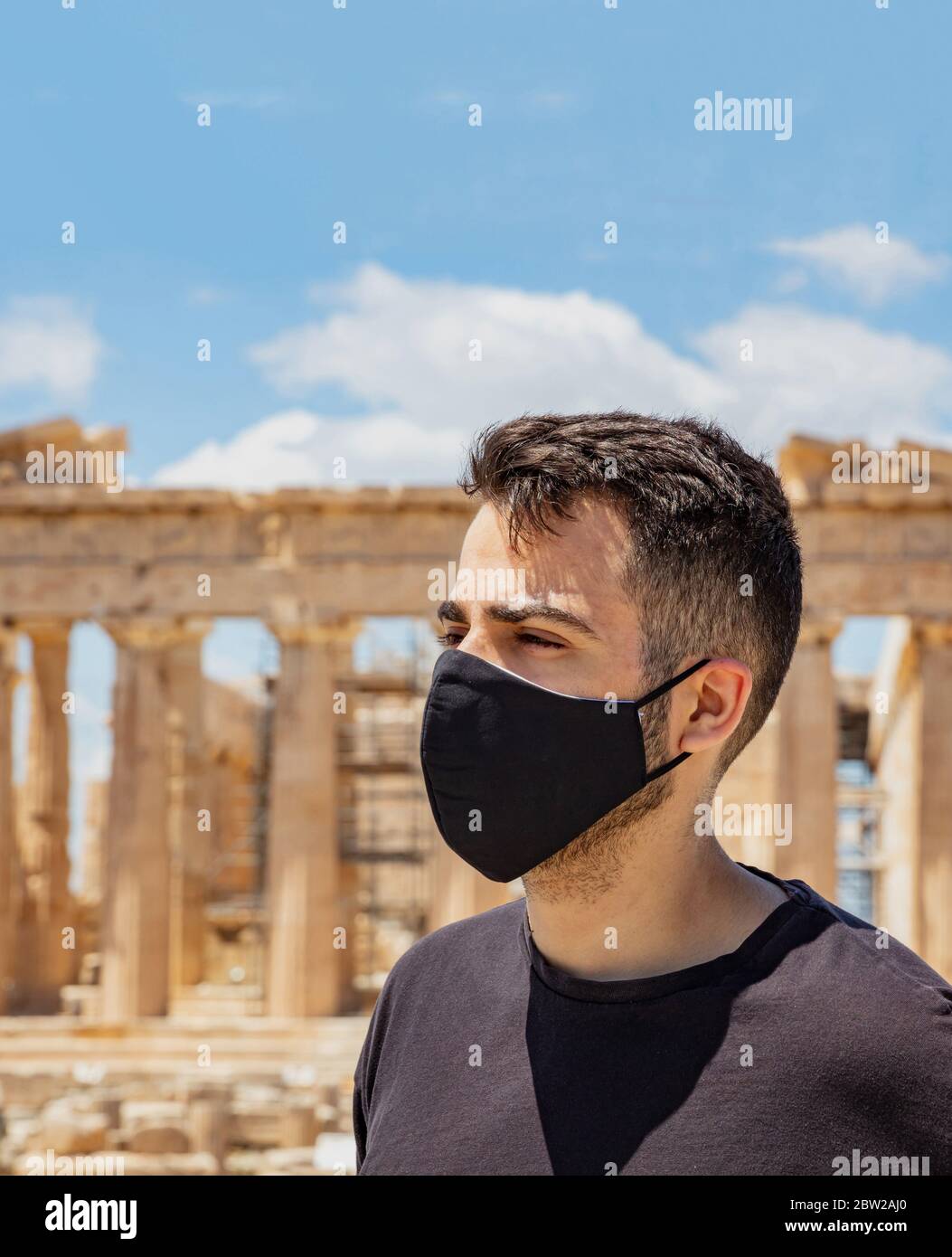 Athènes Acropolis, Grèce coronavirus Days. Jeune homme portant un masque protecteur, un temple grec ancien Parthénon et un fond bleu ciel. Banque D'Images