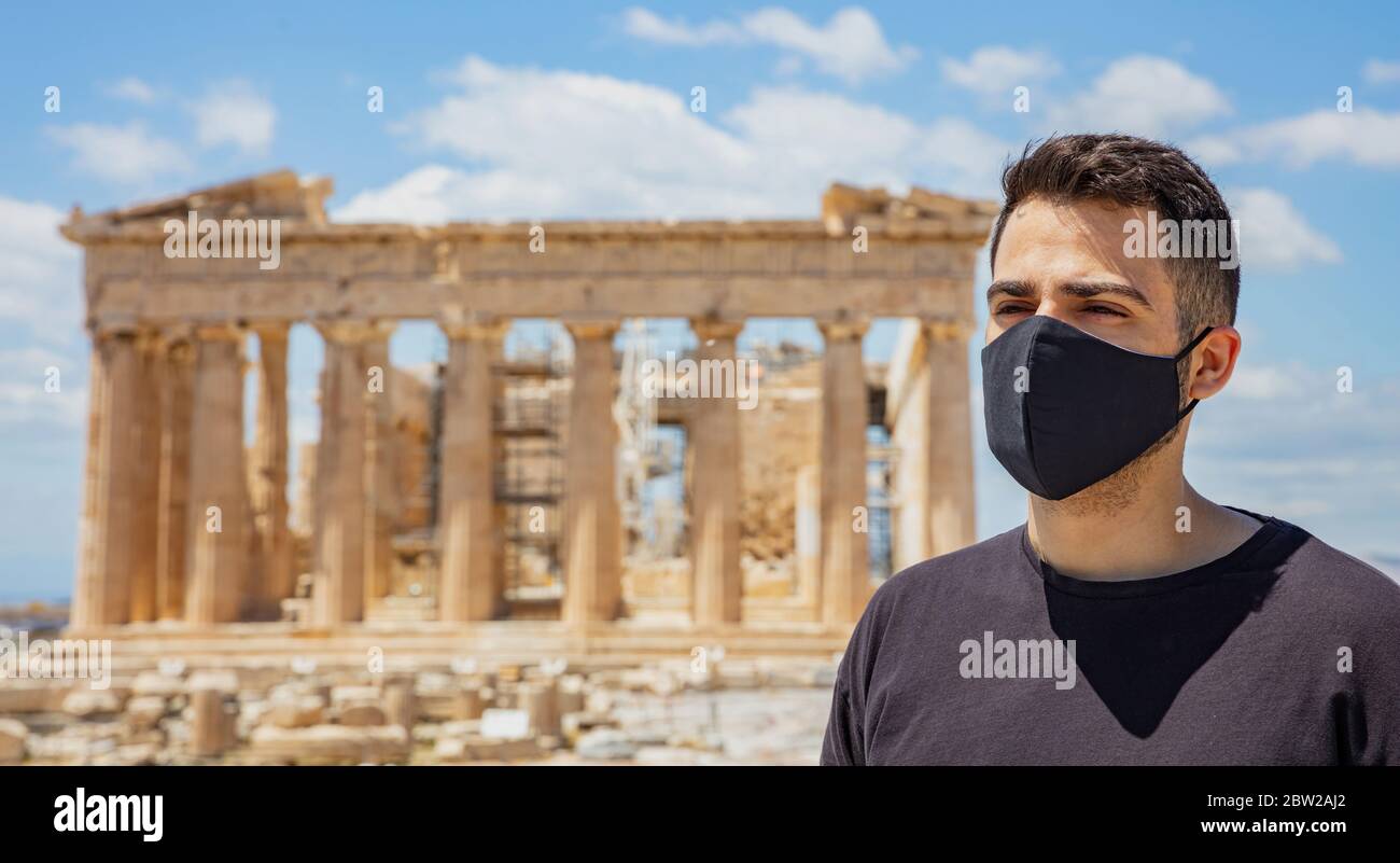 Athènes Acropolis, Grèce coronavirus Days. Jeune homme portant un masque protecteur, un temple grec ancien Parthénon et un fond bleu ciel. Banque D'Images