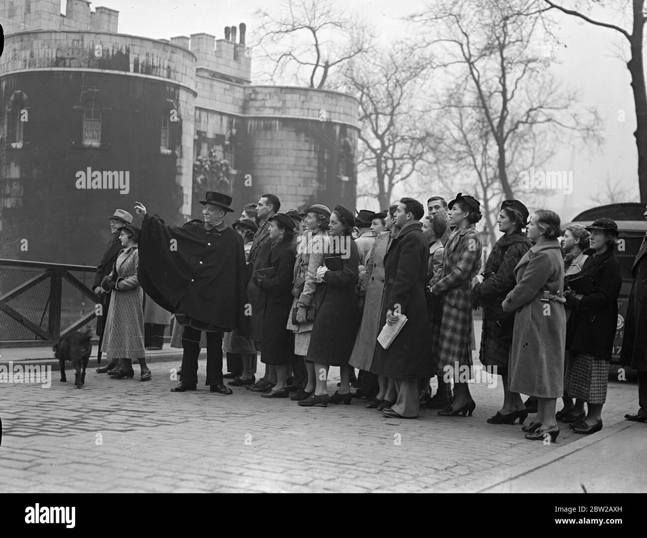 Étudiants sud-africains à la Tour de Londres. Les membres d'un groupe de 70 étudiants des universités sud-africaines qui sont en visite à Londres, ont fait une visite d'inspection à la Tour de Londres. Les visiteurs venaient des universités de Rhodes, du Cap, de Witwatersrand, de Stellenbosch, de Pretoria, de Bloomfontein et de Meritzburg, ainsi que du Howard College of Engineering. Leur programme en Angleterre a été organisé par l'Union nationale des étudiants. La fête fera plus tard le tour du continent. Expositions de photos, un Yeomen de la Garde agissant comme un guide pour les visiteurs sud-africains à la Tour. 28 décembre 1937 Banque D'Images