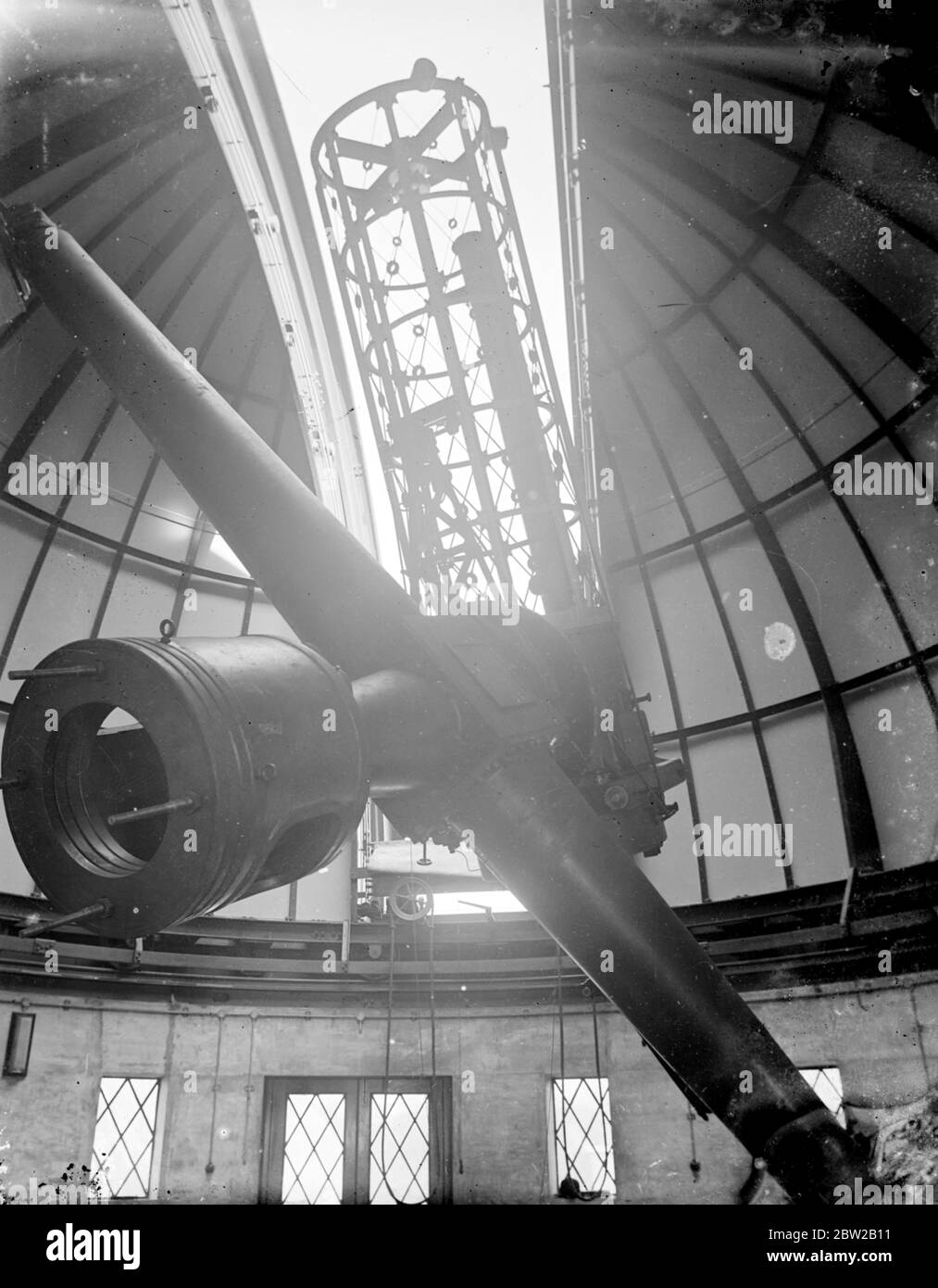 Un nouveau télescope géant pour mesurer la chaleur des étoiles au moyen de photographies a été installé à l'Observatoire de Greenwich, à Londres. La lumière des étoiles tombe sur le miroir et passe ensuite plusieurs fois du réflecteur à réfléchir et à une prison jusqu'à ce qu'elle atteigne enfin la plaque photographique. Le miroir du télescope mesure 36 pouces de diamètre et 6 pouces d'épaisseur et pèse 500 livres. Il a fallu deux ans pour faire. Le dôme mesure 34 pieds de diamètre et l'observateur peut contrôler tous les instruments complexes d'une simple pression sur un bouton. 17 avril 1934 Banque D'Images