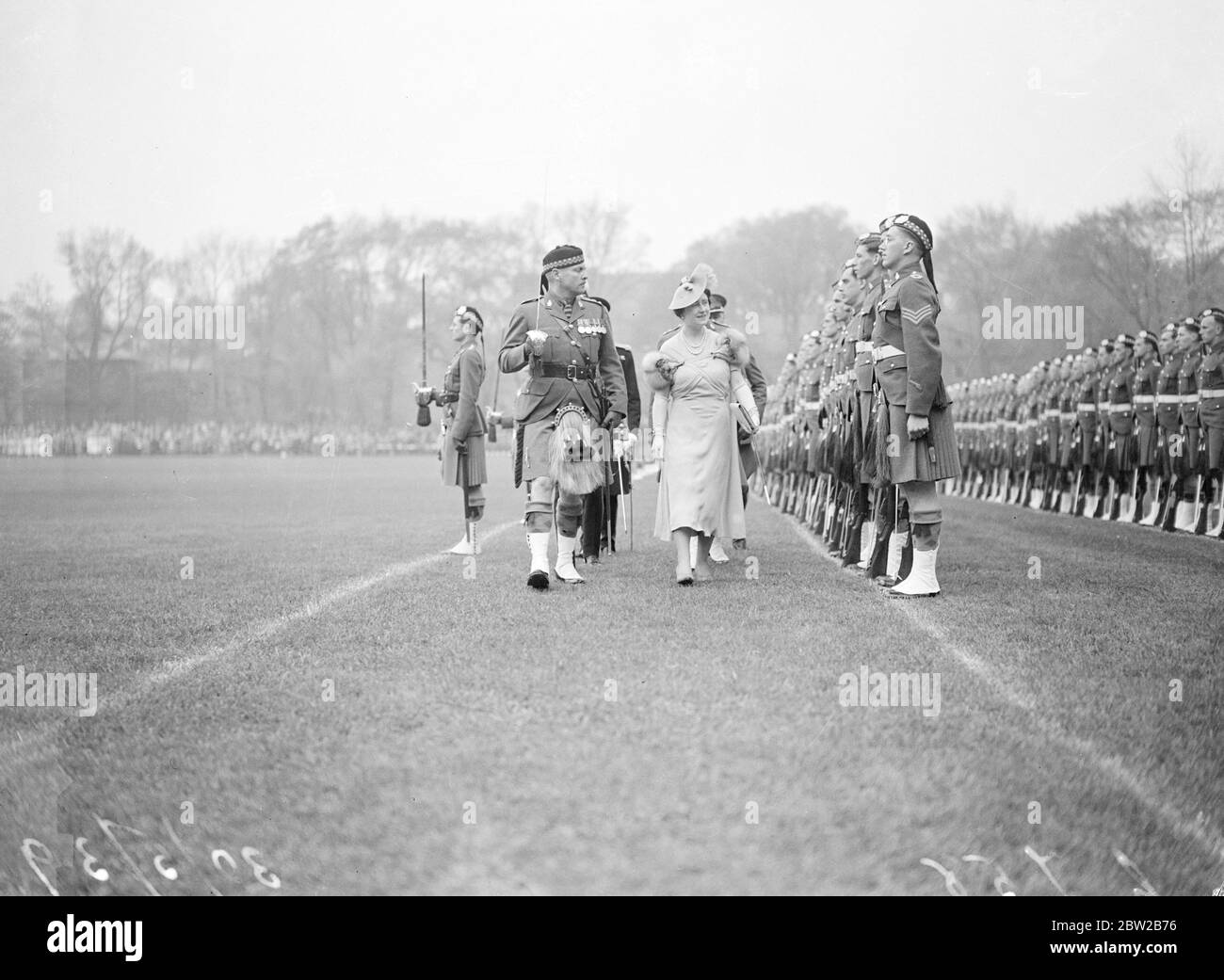 La Reine a présenté des couleurs au Toronto Scottish Regiment, sur le campus nord de l'Université de Toronto. La Reine est le colonel honoraire du London Scottish, auquel le Toronto Regiment est associé. La photo montre la Reine inspectant le défilé. Le lieutenant-colonel C. Thomson commandant le régiment est avec sa Majesté. 30 mai 1939 Banque D'Images