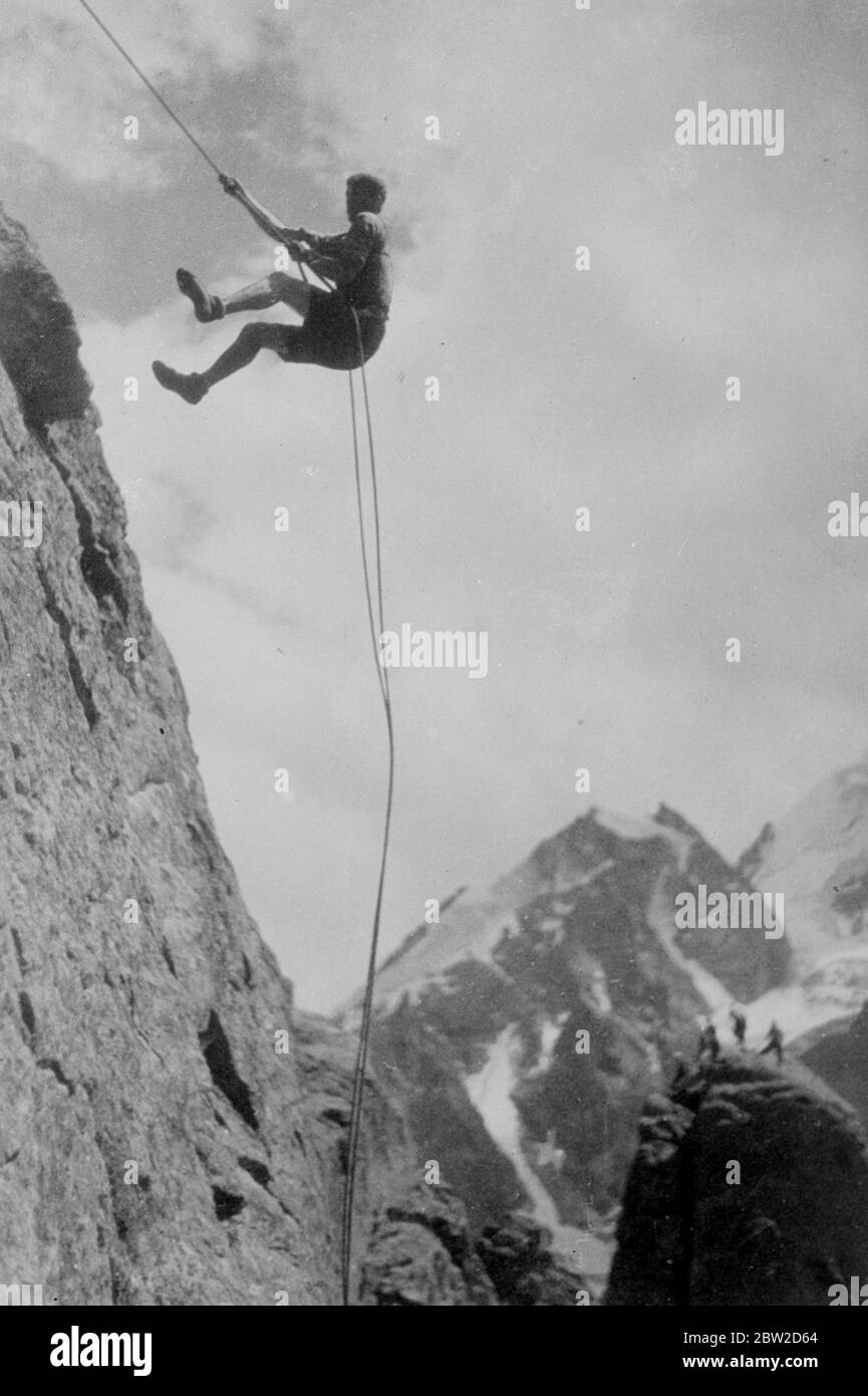 Un alpiniste, qui se balance dangereusement sur une corde étroite entre le ciel et la terre, monte le côté sauvage du mont Elbrus, le plus haut sommet du Caucase, en URSS. Le MT Elbrus mesure 18,526 pieds de haut. Le grimpeur monte le côté de la montagne par la méthode du pendule 27 octobre 1938 Banque D'Images