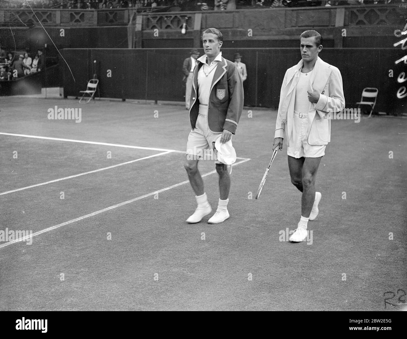 Bunny Austin (à gauche) et Frank Parker qui marchent sur le terrain à Wimbledon. H.W (Bunny) Austin, de Grande-Bretagne, a remporté les deux premiers matchs de Frank Parker lors du premier match entre l'Angleterre et l'Amérique lors du tournoi de la coupe Davis à Wimbledon. 24 juillet 1937 Banque D'Images