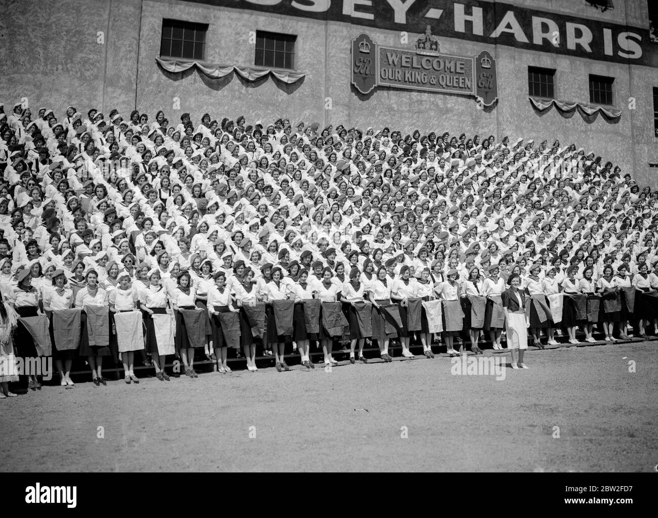 Le roi George VI et la reine Elizabeth lors de leur tournée canadienne de 1939 . Le roi et la reine sont les bienvenus à Saskatoon, en Saskatchewan, par des jeunes filles d'université portant des carrés en soie rouge, blanche et bleue en formation de l'Union Jack. Banque D'Images