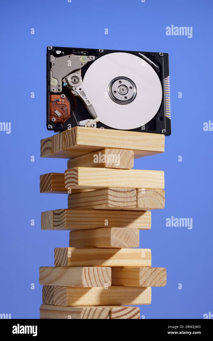 Un disque dur d'ordinateur équilibré sur une pile de blocs de bois Banque D'Images