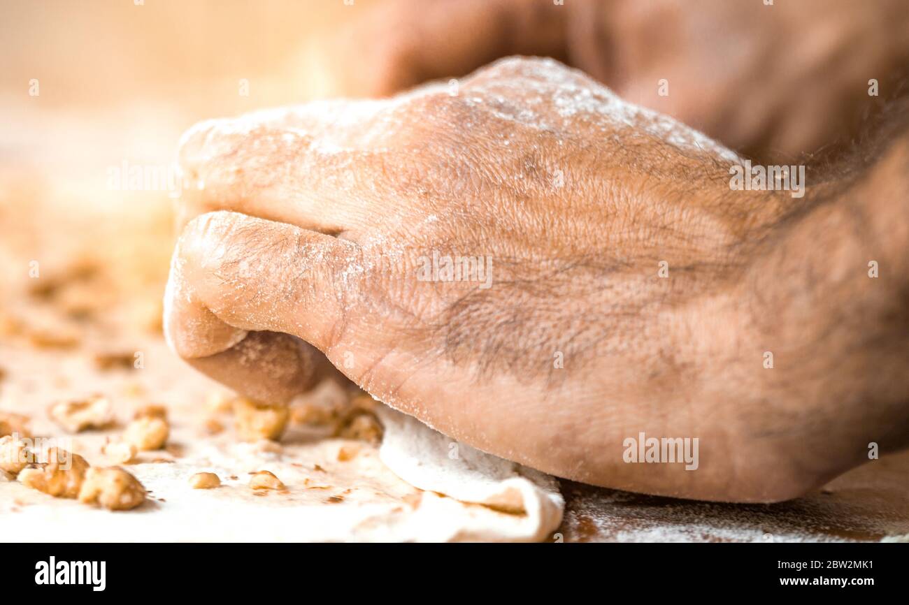 Les mains de sexe masculin roulent la pâte sur la table de cuisine Banque D'Images