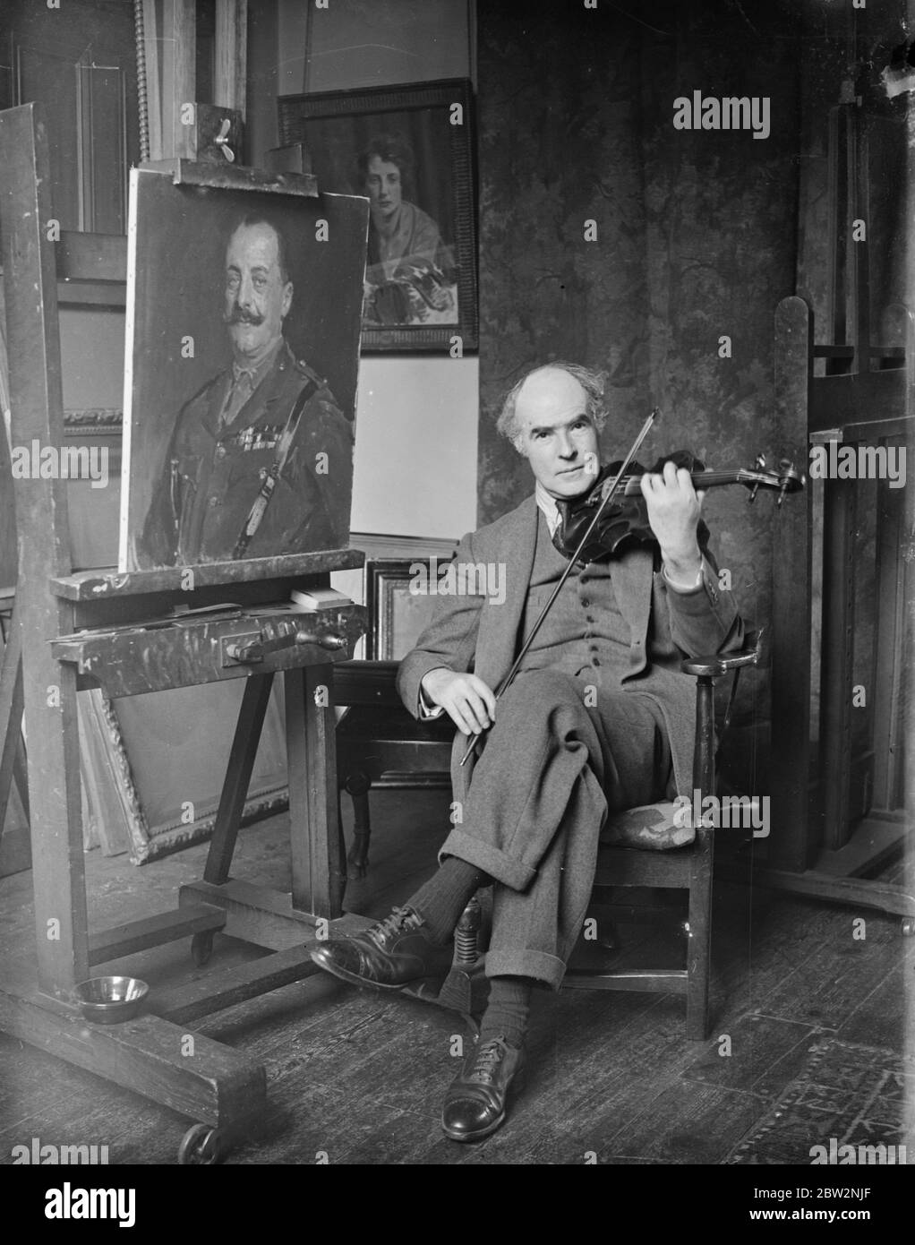 M. Reginald Eves doit soumettre à nouveau des photos à l'Académie royale . Malgré le fait que ses photos ont été rejetées l'année dernière sur le terrain que certaines de ses scènes architecturales ont été peintes sur une base photographique , M. Reginald Eves s'attend à soumettre certaines de ses œuvres comme lecture au comité suspendu de l'Académie Royale . Il est busily au travail dans son studio de préparation à l'académie . M. Reginald Eves , qui est un ardent musicien , jouant son violon dans son studio à côté de son dernier ouvrage , un portrait de Lord Fitzwilliam , qu'il peut soumettre pour l' Académie Royale de cette année . 24 février 1932 30 Banque D'Images