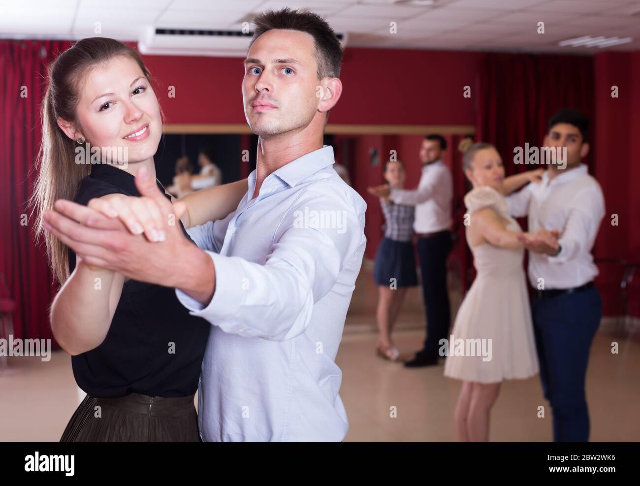 Smiling couples de danseurs appréciant foxtrot dans un studio de danse Banque D'Images