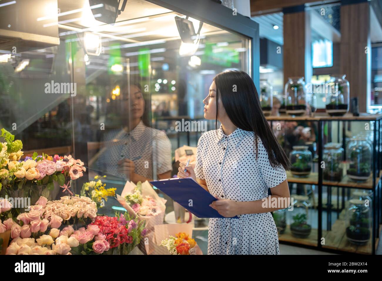 Brunette femme regardant des fleurs, prenant des notes Banque D'Images