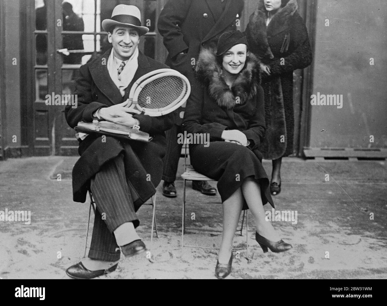 René Lacoste de nouveau au tennis . René Lacoste , la star française du tennis et champion international qui a figuré si bien en vue dans la victoire de la coupe Davis pour la France , Mais qui a été en retraite , a assisté au tournoi inter-ville de Paris Londres avec sa femme tout aussi célèbre , l'ancienne Mlle Thion de la chaume , le champion de golf . René Lacoste a porté deux raquettes et a donné lieu à des spéculations sur la possibilité de sa participation à la défense de la coupe Davis cette année . René Lacoste et son épouse sur la touche lors du match de Paris à Londres . 19 mars 1932 . Banque D'Images