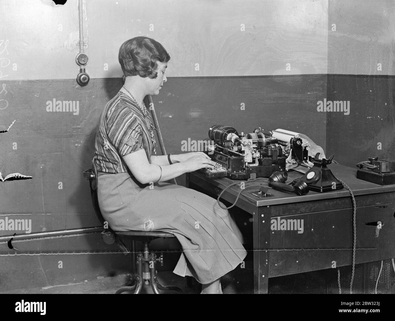 Système de téléimprimante inauguré au bureau central de poste . Le système de communication téléimprimeur qui fonctionne en conjonction avec le téléphone et permet à l'abonné de transmettre un message sur les lignes téléphoniques à l'aide d'un téléimprimeur dans le secret parfait a été inauguré à Londres . Envoi d'un message sur le téléimprimeur au Bureau général de poste , Londres . 15 août 1932 Banque D'Images