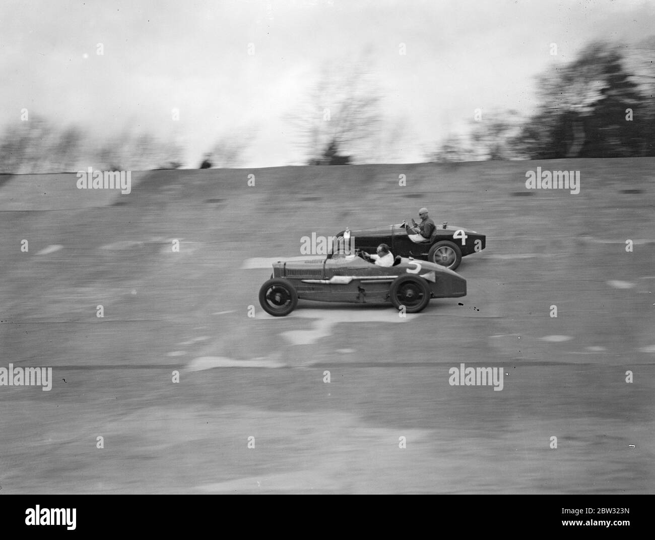 Une course à Brooklands . La foule a fait un pas sur la piste Brooklands pour la grande réunion d'ouverture du lundi de Pâques lorsque Sir Malcolm Campbell a sorti son Bluebird sur la piste . M. C Penn Hughes dans son Bugatti et M. E L Bouts dans son Sunbeam ( caméra la plus proche ) course nexk et cou autour de la piste dans la course de Norfolk éclair handicap court . . 28 mars 1932 Banque D'Images