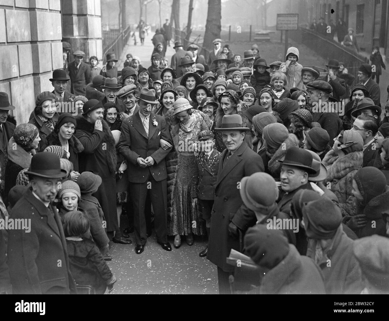 Record dans la ruée du mariage de Pâques à Hackney . Tous les records ont été brisés pour la ruée des mariages de Pâques à l'hôtel de ville Hackney Old Town Hall quand quarante couples ont été mariés le samedi matin de Pâques . M. et Mme Ernest Bellinger partent après leur mariage à travers la foule qui s'est rassemblée pour voir le nombre record de couples mer . 26 mars 1932 Banque D'Images