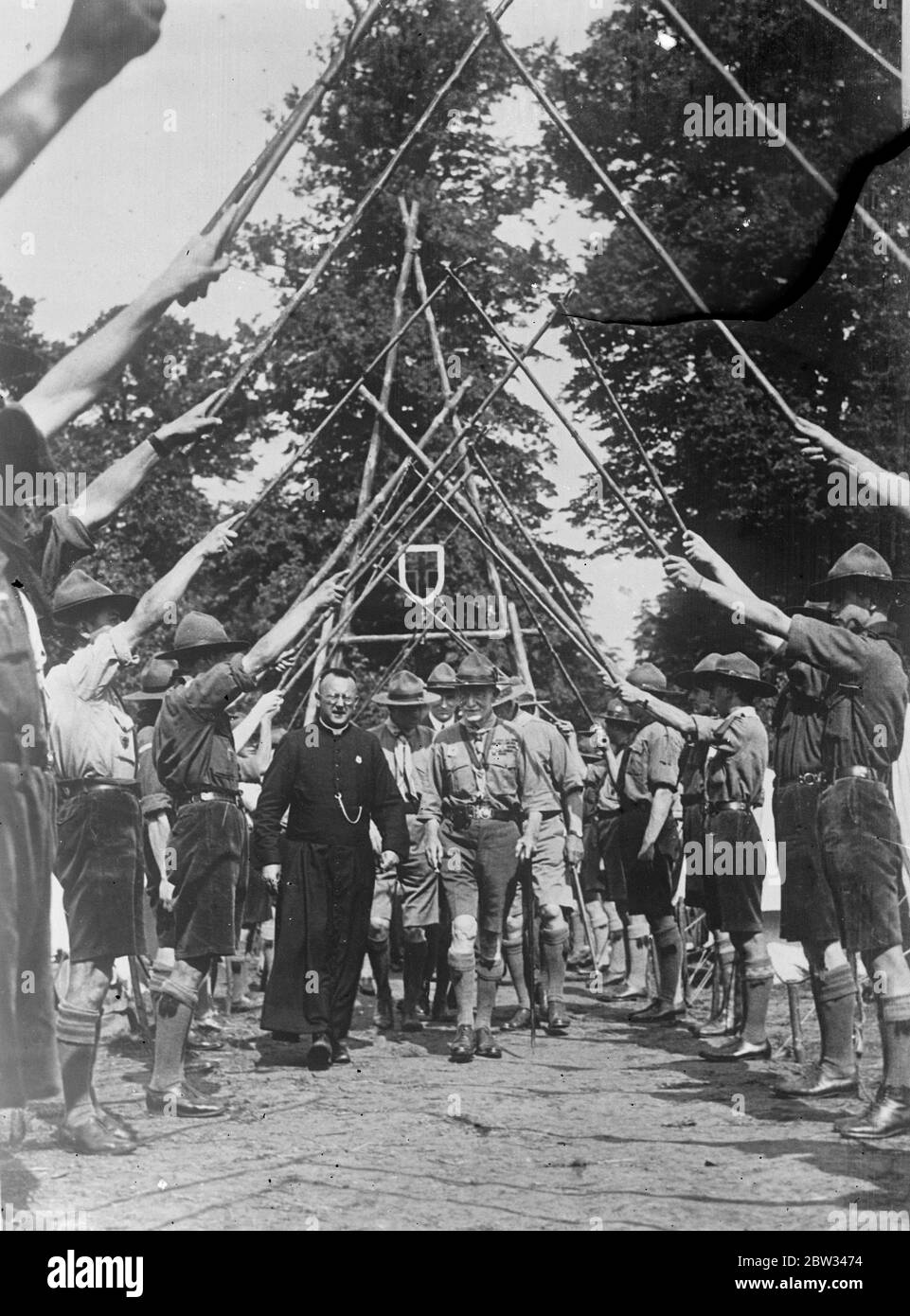 Lord Baden Powell en Hollande . Lord Baden Powell , le scout en chef , a effectué une visite au grand camp scout de Wassenaar , près de la Haye , Hollande . Lord Baden Powell , accompagné d'un évêque , entrant dans le campement catholique romain sous une arcades de pôles scouts pendant sa visite . 15 août 1932 Banque D'Images