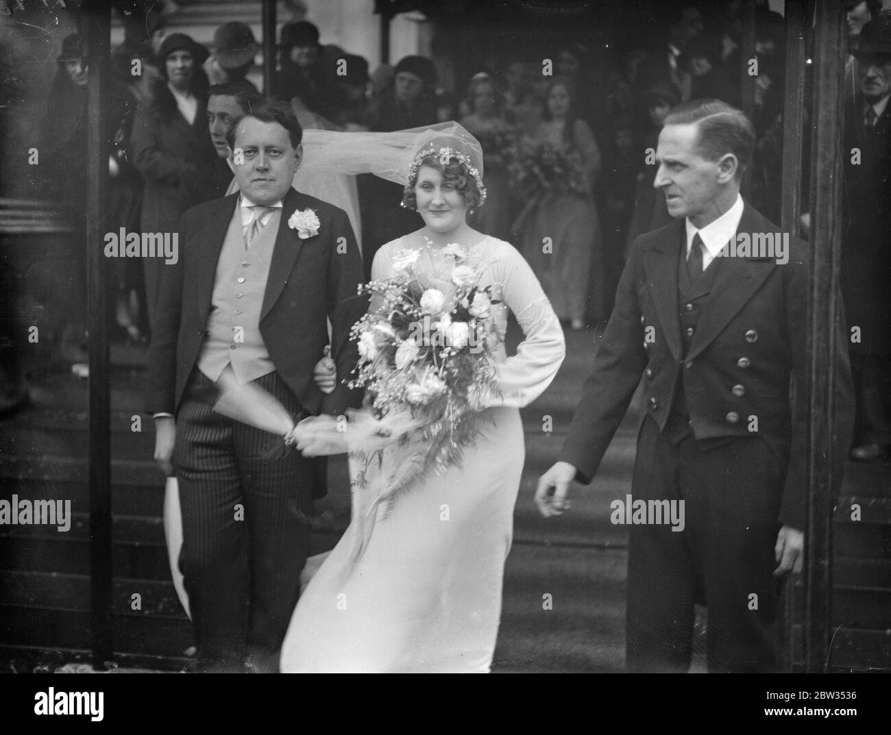 Le mariage a eu lieu à Brompton Oratoire , Londres , de M. John Douglas Woodruff , auteur de Wodstock Road , Oxford , et de l'honorable Marie Ibmaculee Antoinete Lyon Dalberg Acton , fille aînée du regretté Lord et Lady Acton , Et soeur du Seigneur actuel Acton . M. Woodruff a 35 ans et celui de sa mariée 27 ans. Le voile de la mariée souffle dans le vent alors qu'elle quittait l'église avec le marié . 25 février 1933 Banque D'Images