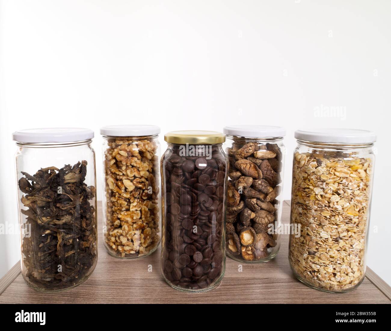 Stockage des aliments en vrac dans des pots en verre : champignons sauvages secs, muesli, chocolat et noix. Concept zéro déchet. Banque D'Images