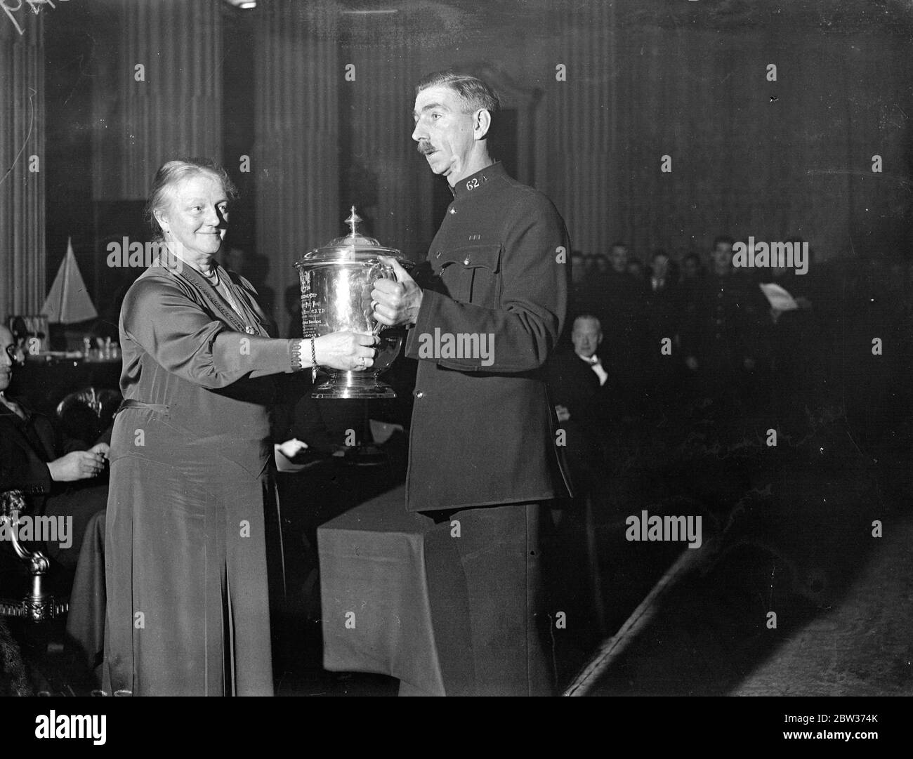 Lord Mayor présente des prix aux athlètes de police . Le Lord Mayor de Londres , Sir Charles H Collett , a présenté les prix remportés par des membres du City of London police Athletic Club , au Mansion House . Photos ; la Dame Mayoress présentant la coupe Colonel Matthey pour le tir au pistolet à l'agent Nash , qui a également remporté le championnat de tir au fusil de club . 13 décembre 1933 Banque D'Images
