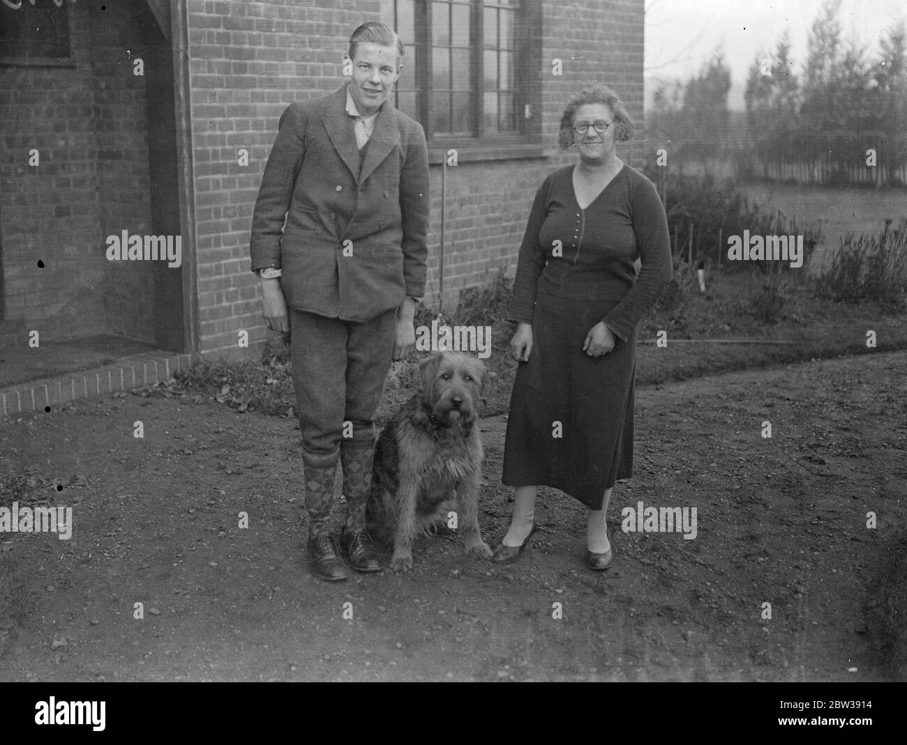 Chien donne l'alarme et sauve quatre vies dans le feu . Un chien Airedale qui dort dans le hall la nuit, a routé le foyer quand le feu a éclaté au rez-de-chaussée de la maison de M. Stanley Harris Bomer à Ham Common . L'épidémie s'est produite dans les salons au rez-de-chaussée et le chien s'est précipité à l'étage et a réveillé M. Somers en se écartant à la porte de sa chambre à coucher . Le chien , Ruff , a sauvé la vie de M. Somers , de Mme Somers et de leur fils de 17 ans et de leur fille de 19 ans . Photos ; Mme Somers avec son fils , Jack et chien , Ruff . 11 janvier 1934 30, 30, 30, 30, 30, 30, 30, 30, 30, 30 Banque D'Images