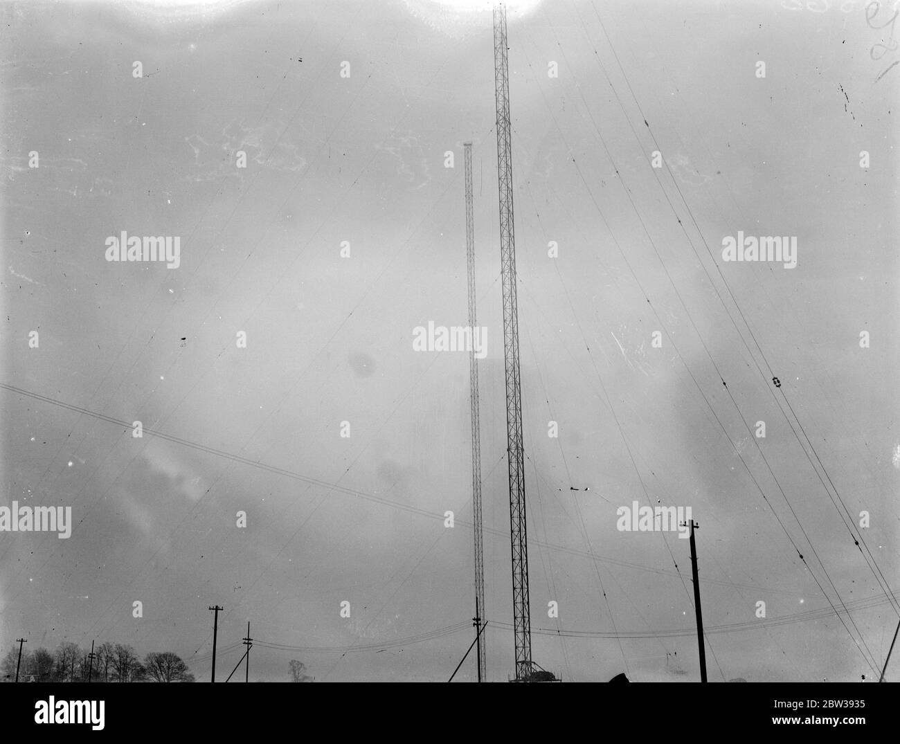 Le nouveau géant de la BBC prend forme à Droitwich . Grand émetteur ' s 700 pieds tours aériennes . Les grands mâts d'acier de 700 pieds de haut , le plus haut jamais mis en place par la BBC pour la nouvelle station de radiodiffusion de haute puissance à Droitwich , Worcestershire , ont maintenant été achevés . La station qui est entourée par un air ' hush hush ' , sera prête pour l'opération en été . Cet émetteur national dispose d'une puissance aérienne pouvant atteindre 200 kilomètres et qui est suffisamment puissante pour attirer la plupart des émissions européennes . Chacun des mâts d'antenne est maintenu perpendiculairement par 21 cordes en acier , anchore Banque D'Images