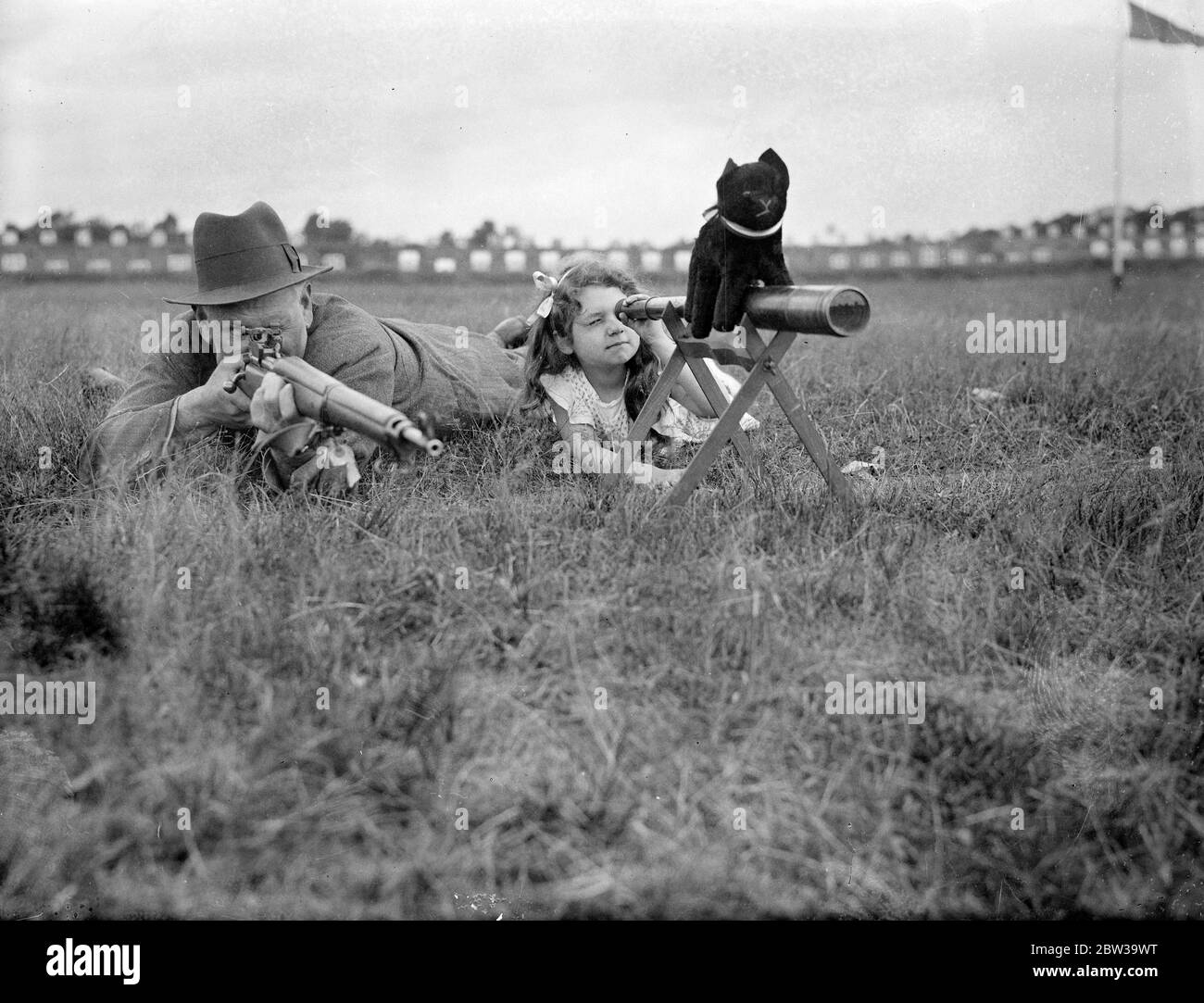 Fille aide le père dans le concours du Prix King à Bisley . La petite fille de M. C H Philpott, Denise, enregistre des hits pour son père . Denise a une mascotte noire pour chat pour la chance . 17 juillet 1935 Banque D'Images