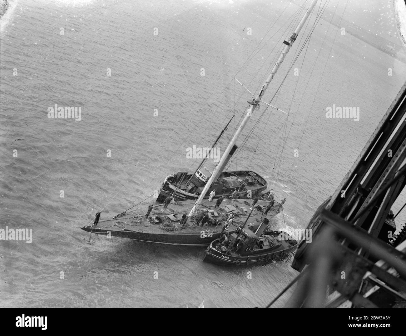 L ' espoir de yachting de Grande-Bretagne a son mât mis en place par grue géante . M. T O M Sopowy ' s America ' s Cup challenger a été remorqué à Portsmouth Dockyard pour faire marcher son mât ' ou mis en place . Le mât géant , qui est , comme la coque , en acier , est de 167 pieds de haut , presque la même colonne que Nelson ' s dans Trafalgar Square , Londres . Photos montre , regardant vers le bas sur le pont de l'Endeavour , l'espoir de la Grande-Bretagne qui hurlait comme son mât a été placé en position . Cette photo a été prise du sommet de la grue géante . 20 avril 1934 . Banque D'Images