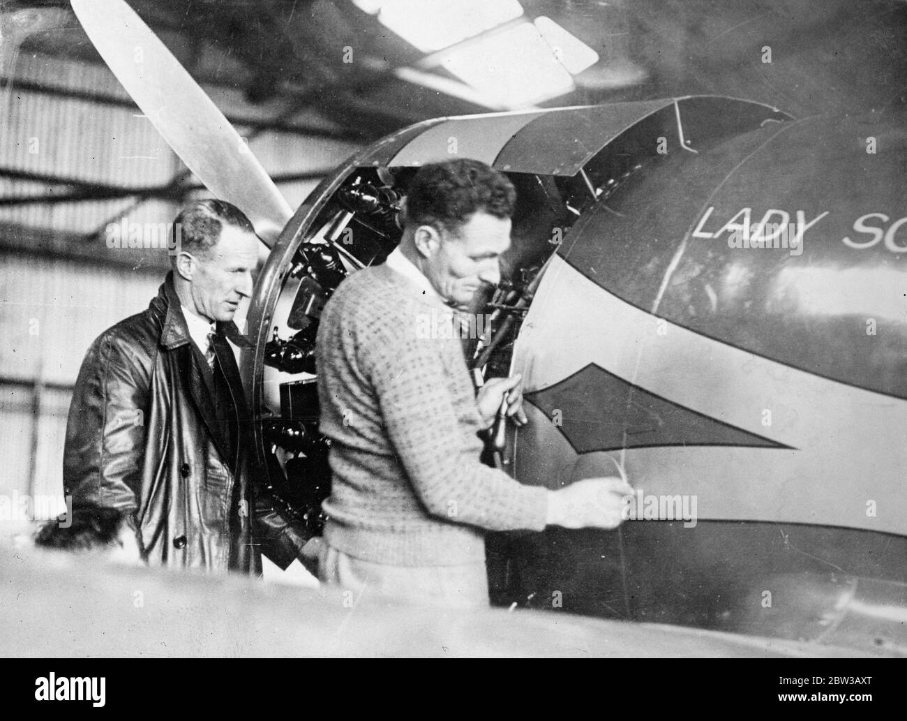 Kingsford Smith et son compagnon inspectent son avion endommagé de course de Melbourne ' Lady Southern Cross ' . 1er octobre 1934 Banque D'Images