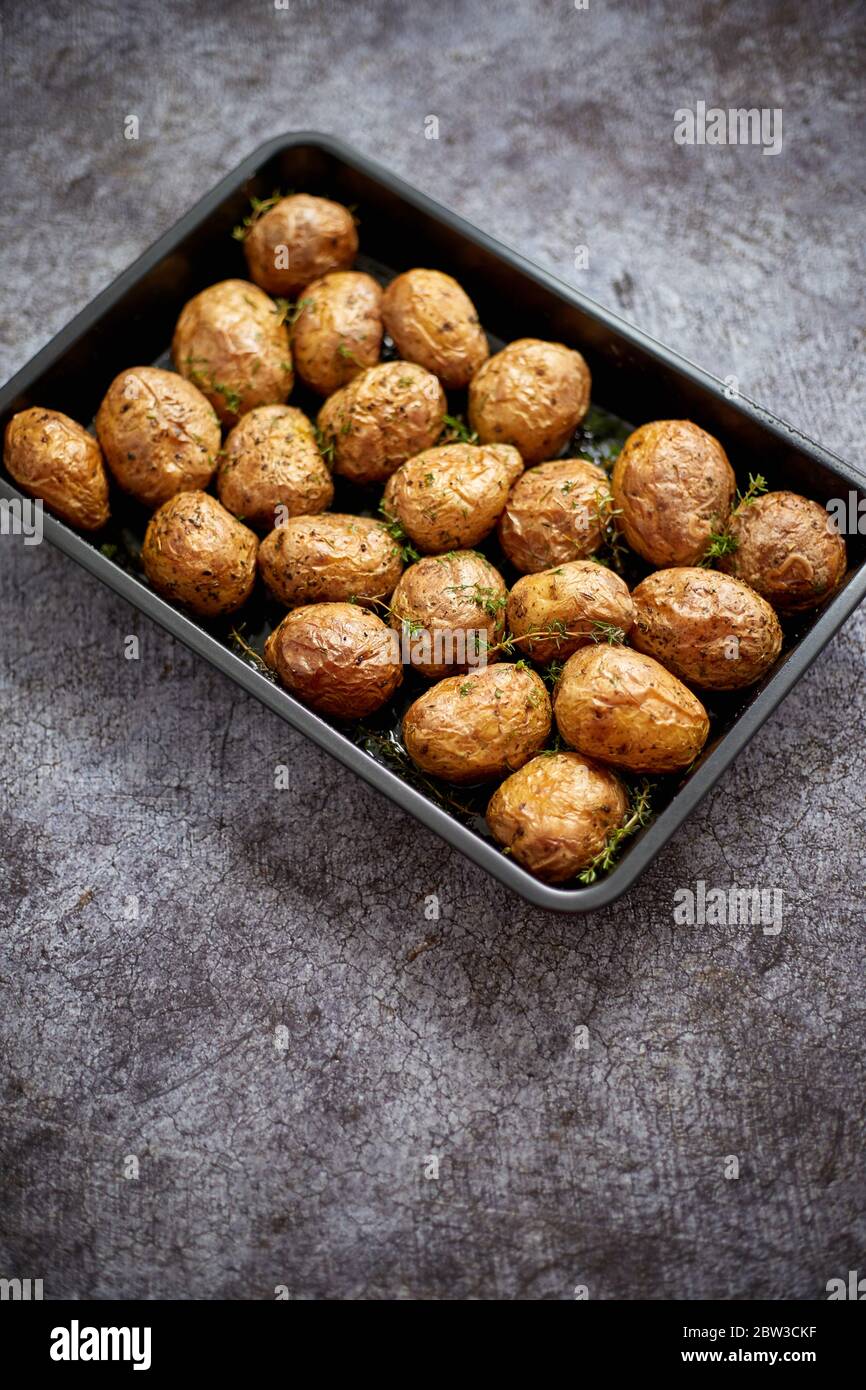 Pommes de terre entières rôties faites maison en vestes. Avec beurre, romarin et thym. Servi dans un plat métallique Banque D'Images