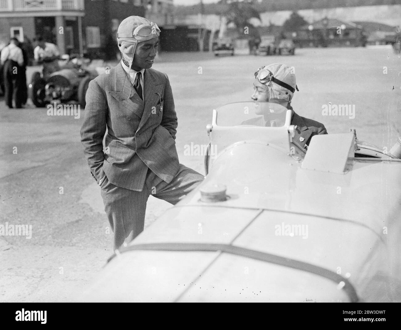 Les Princes de Siam à la course à Brooklands . Deux Princes de la Maison Royale de Siam , le Prince Bire et le Prince Abhbs , son frère, vont se présenter à la course pour un trophée présenté par le Prince Chula de Siam . La photo montre le prince Bira ( dans le cockpit de sa voiture de course qu'il doit conduire dans la course ) bavardant avec son frère le prince Abhbs avant la pratique . 31 juillet 1935 Banque D'Images