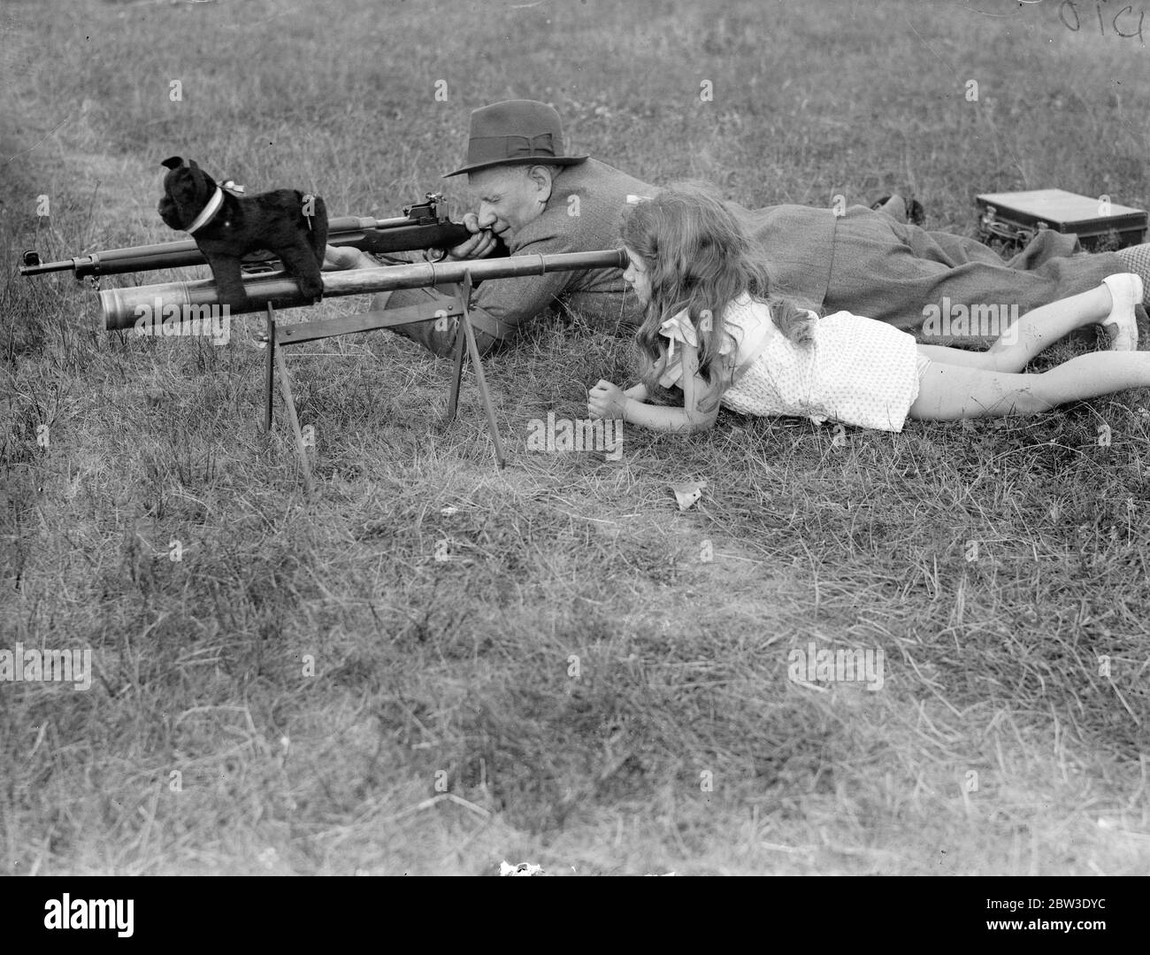 Fille aide le père dans le concours du Prix King à Bisley . La petite fille de M. C H Philpott, Denise, enregistre des hits pour son père . Denise a une mascotte noire pour chat pour la chance . 17 juillet 1935 Banque D'Images