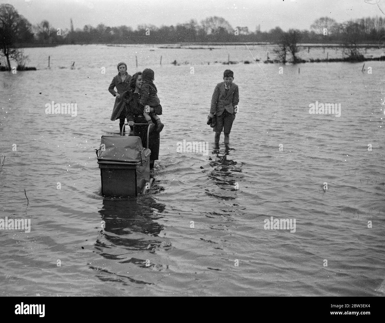 Inondations dans le Berkshire . Une mère avec un bébé et un bébé et d'autres marchant dans l'eau d'inondation près de Reading . 30 décembre 1934 Banque D'Images