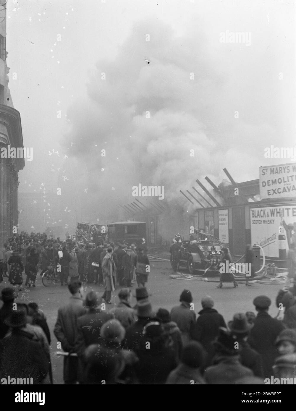 Une foule observe le feu féroce qui a fait feu dans le bâtiment démoli de Tottenham court Road , Londres . 12 janvier 1935 Banque D'Images