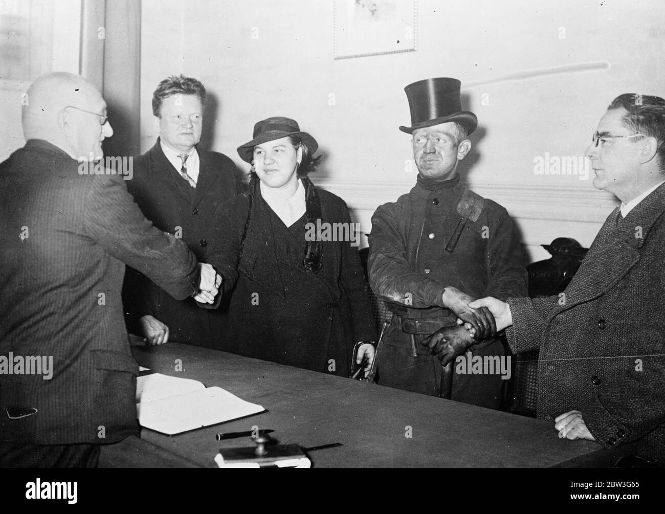 Les choses semblaient noires à l'occasion de ce mariage des épouses. Vêtu de ses vêtements de travail et de son visage et de ses mains toujours engriés de suie , Kurt Jungling , un balai de cheminée de Berlin , a été marié à Frauléin Berta Schuhmacher , un bureau de caisse . Pour annoncer à tous et à divers que c'était vraiment une occasion spéciale , cependant, le marié s'est condended à porter un chapeau de soie . Photos , Kurt Jungling , le marié de balayage de cheminée , et sa mariée recevant les félicitations des officiels après leur mariage . 30 novembre 1935 Banque D'Images