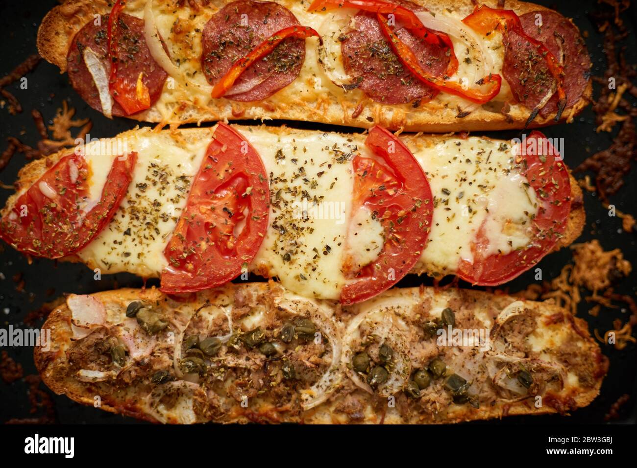 Longues baguettes de pizza avec thon, champignons, tomates et fromage sur un plateau métallique Banque D'Images