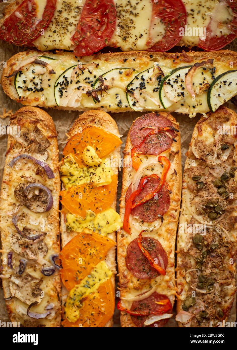Assortiment de sandwichs cuits au four avec garnitures diverses. Avec fromage fondu, légumes, thon, olives épices Banque D'Images