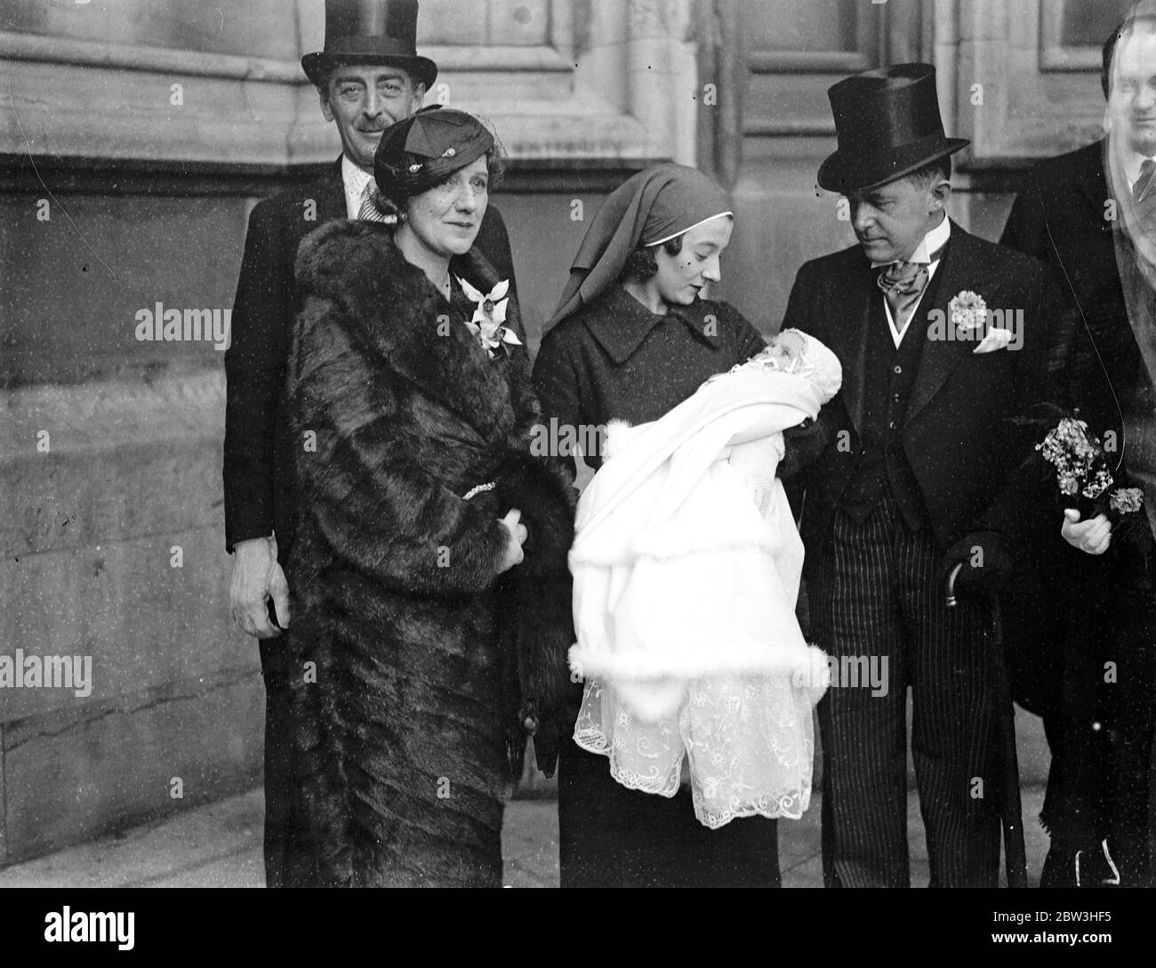 Fils du député baptisé par l'évêque de Gloucester dans la crypte des chambres du Parlement . Mme Leslie Boyce ( en fourrure ) , le bébé dans les bras de son infirmière , M. H Leslie Boyce , député ( à côté de l'infirmière ) et le major Bevan ( à gauche ) après le baptême . 8 février 1935 Banque D'Images