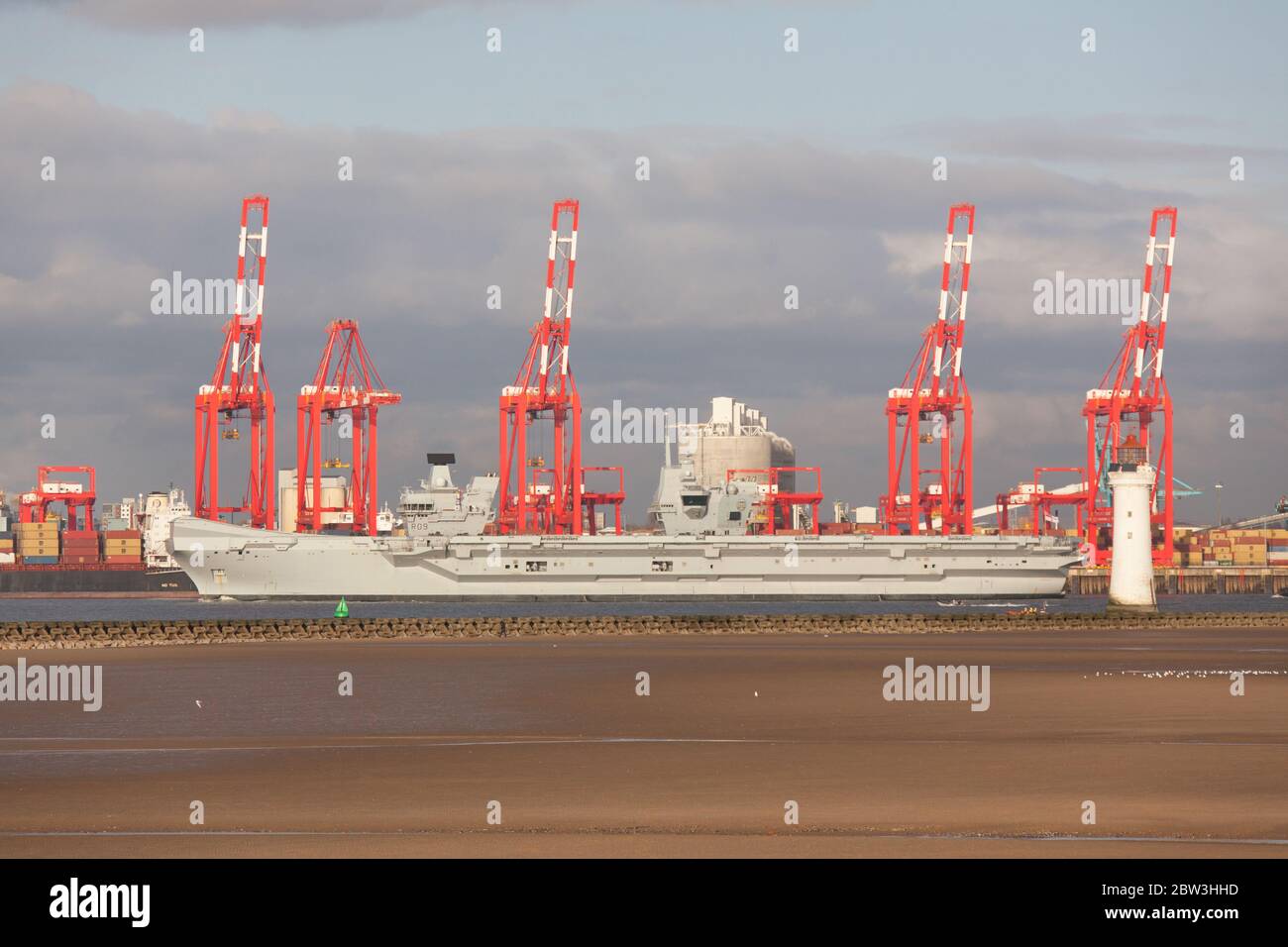 Ville de Liverpool, Angleterre. Le HMS Queen Elizabeth passe devant les grues rouges du terminal de conteneurs de Liverpool, sur la rivière Mersey. Banque D'Images